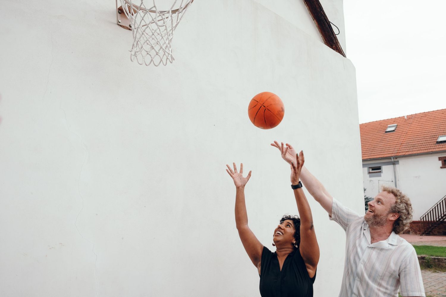 Playful moments of people playing basketball in formal wedding attire.