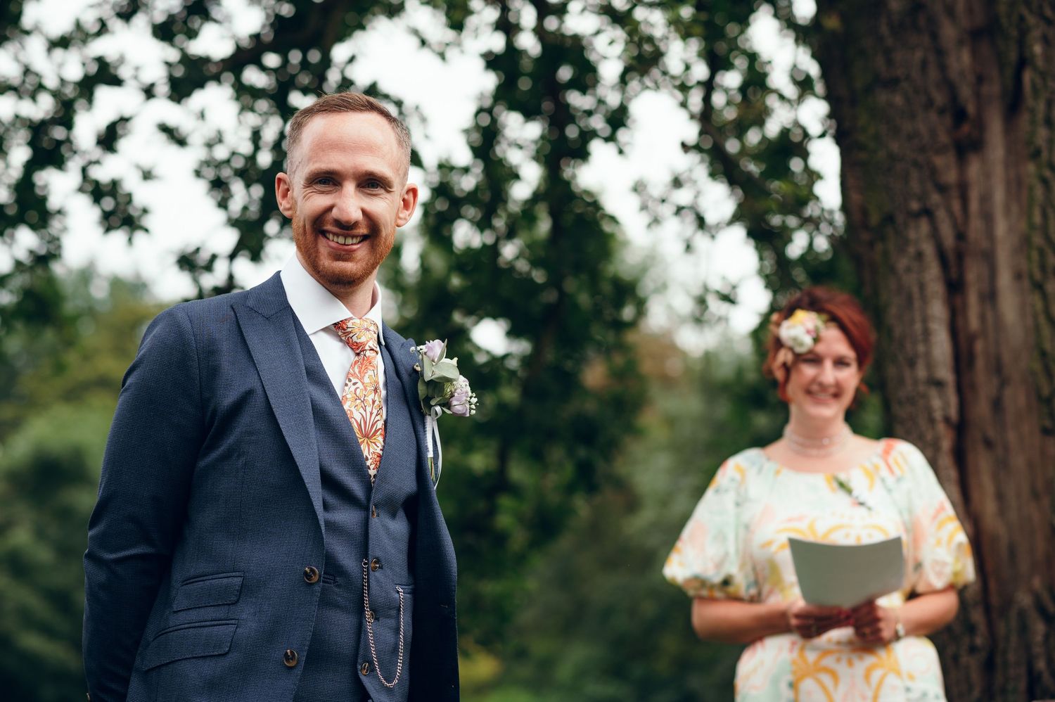 Wedding party members smile and laugh together during outdoor celebration.