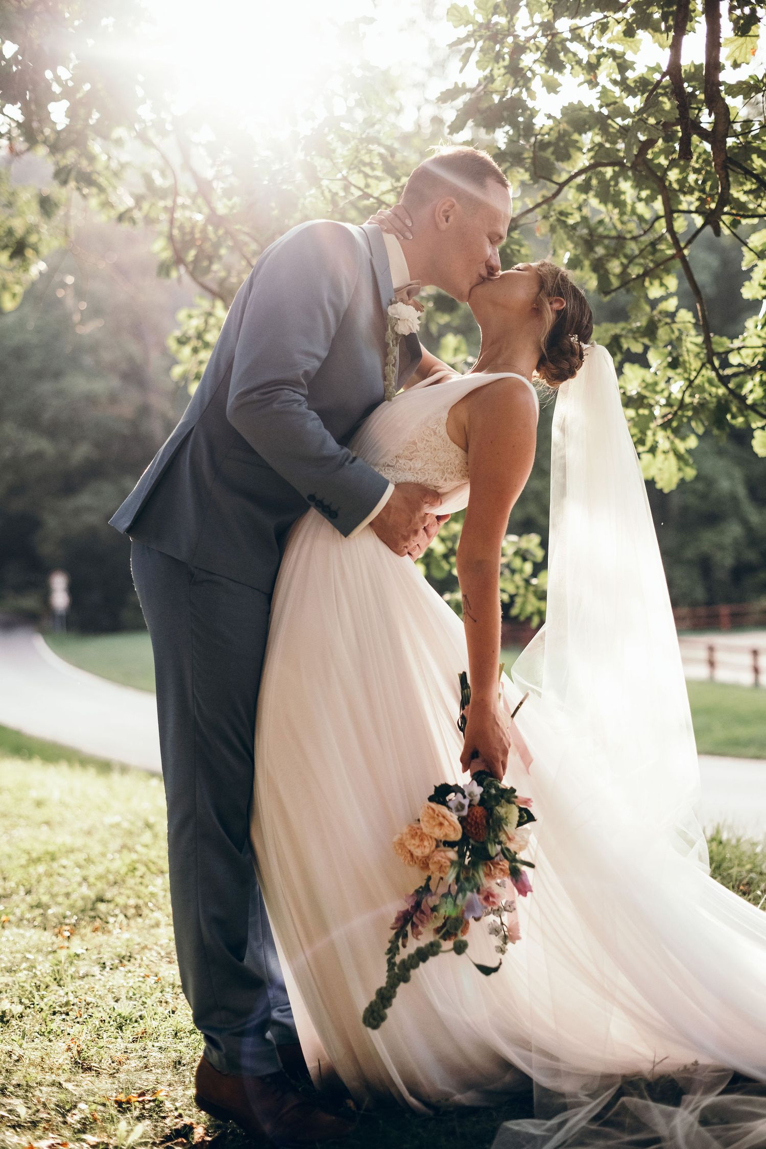 Romantic sunset wedding portraits in natural outdoor setting with floral bouquet.