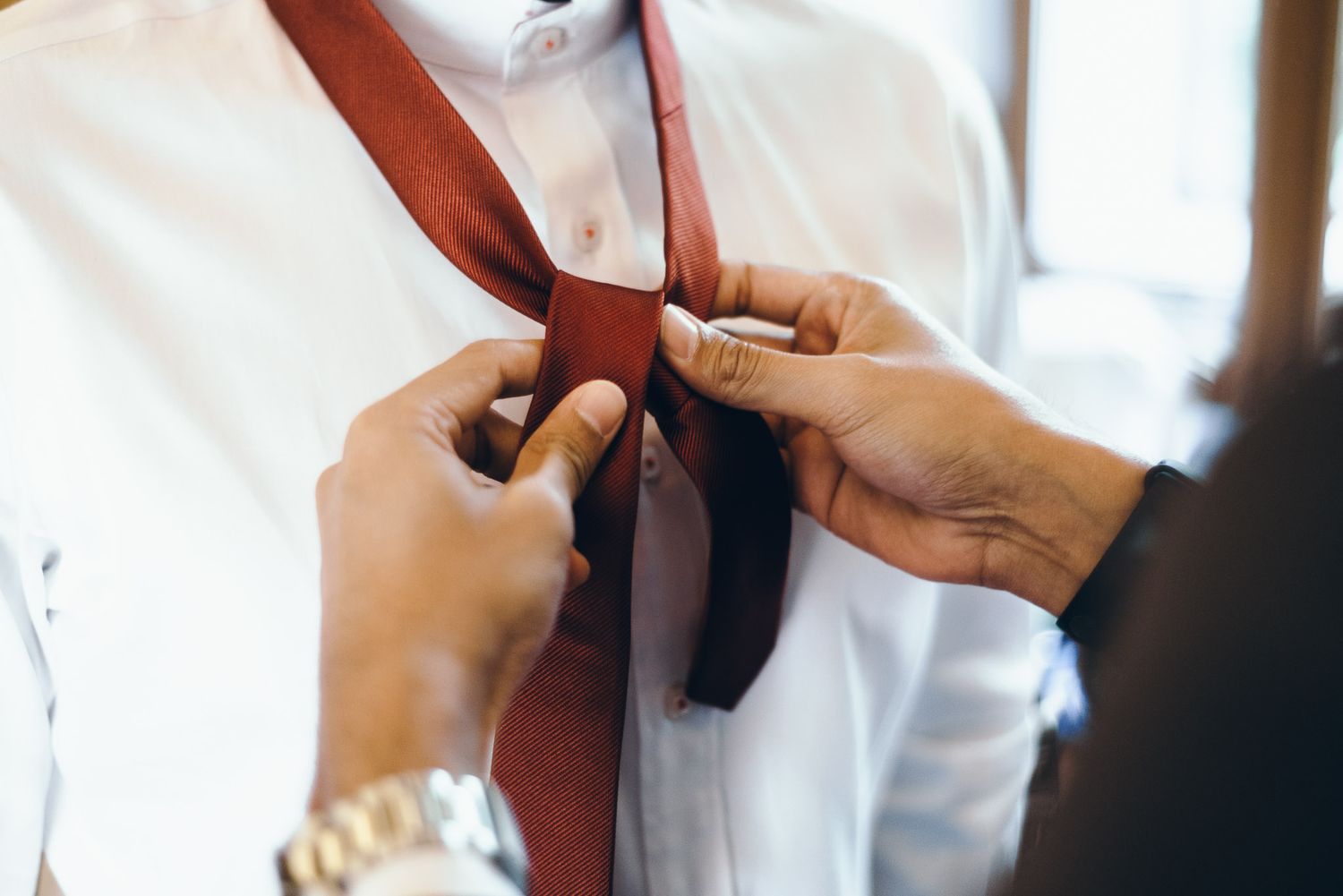 Close-up of formal attire and accessories being adjusted.