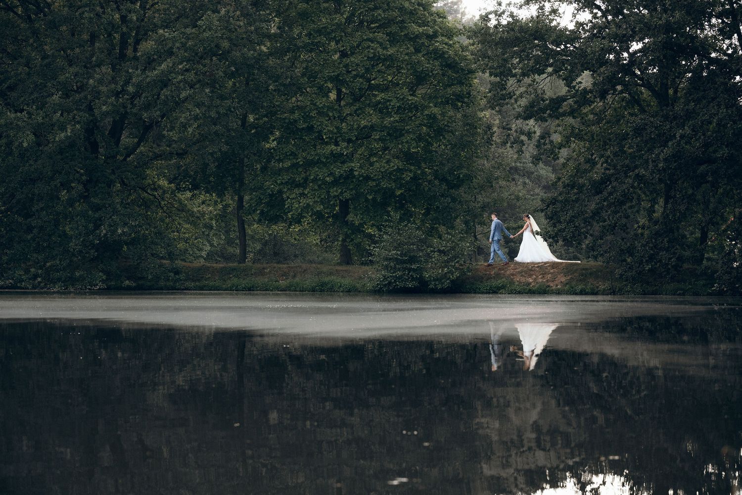 Serene lakeside wedding photography session with reflections on the water.
