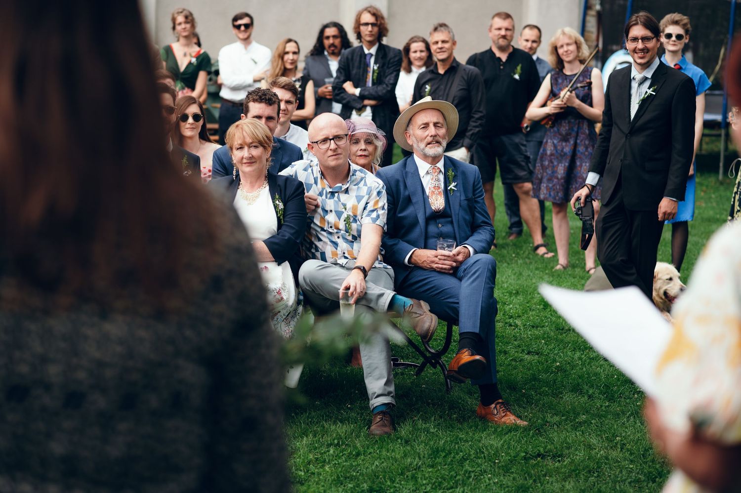 Wedding guests mingle and socialize on a sunny lawn during outdoor reception.