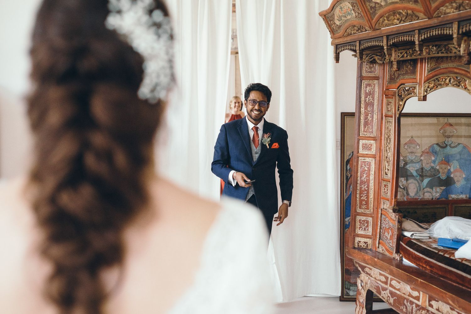 A wedding day first look moment captured in an ornate room with antique furniture.
