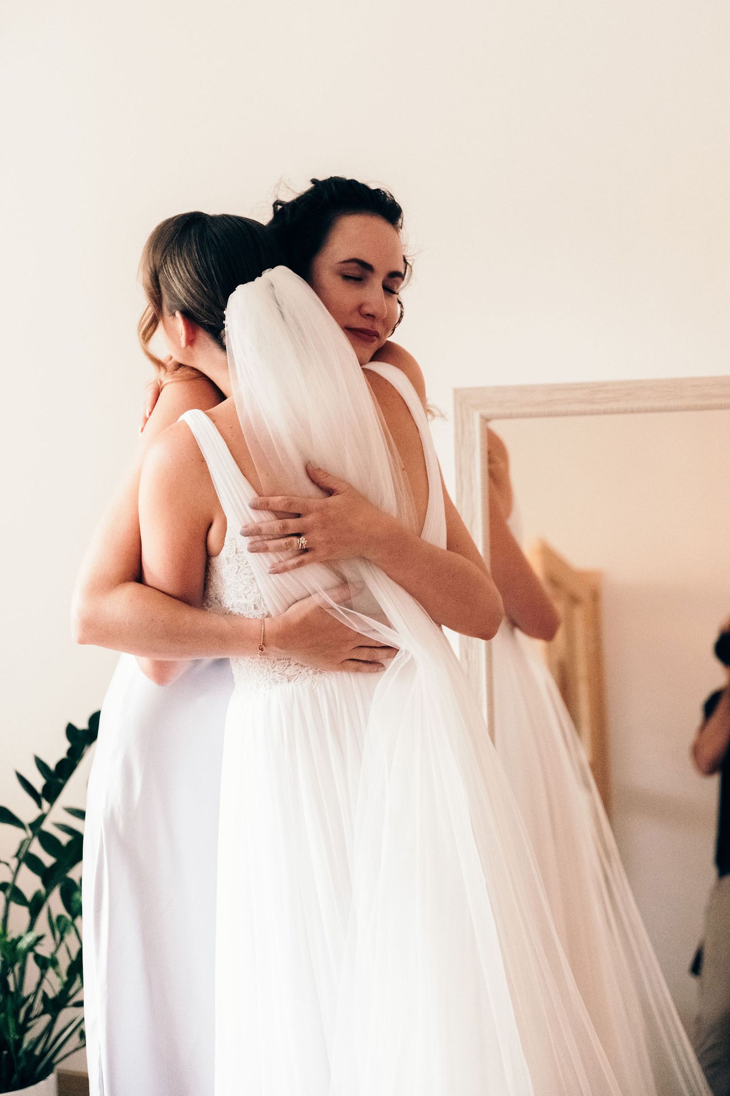 Emotional getting ready moments between mother and daughter on a wedding day in soft natural light.