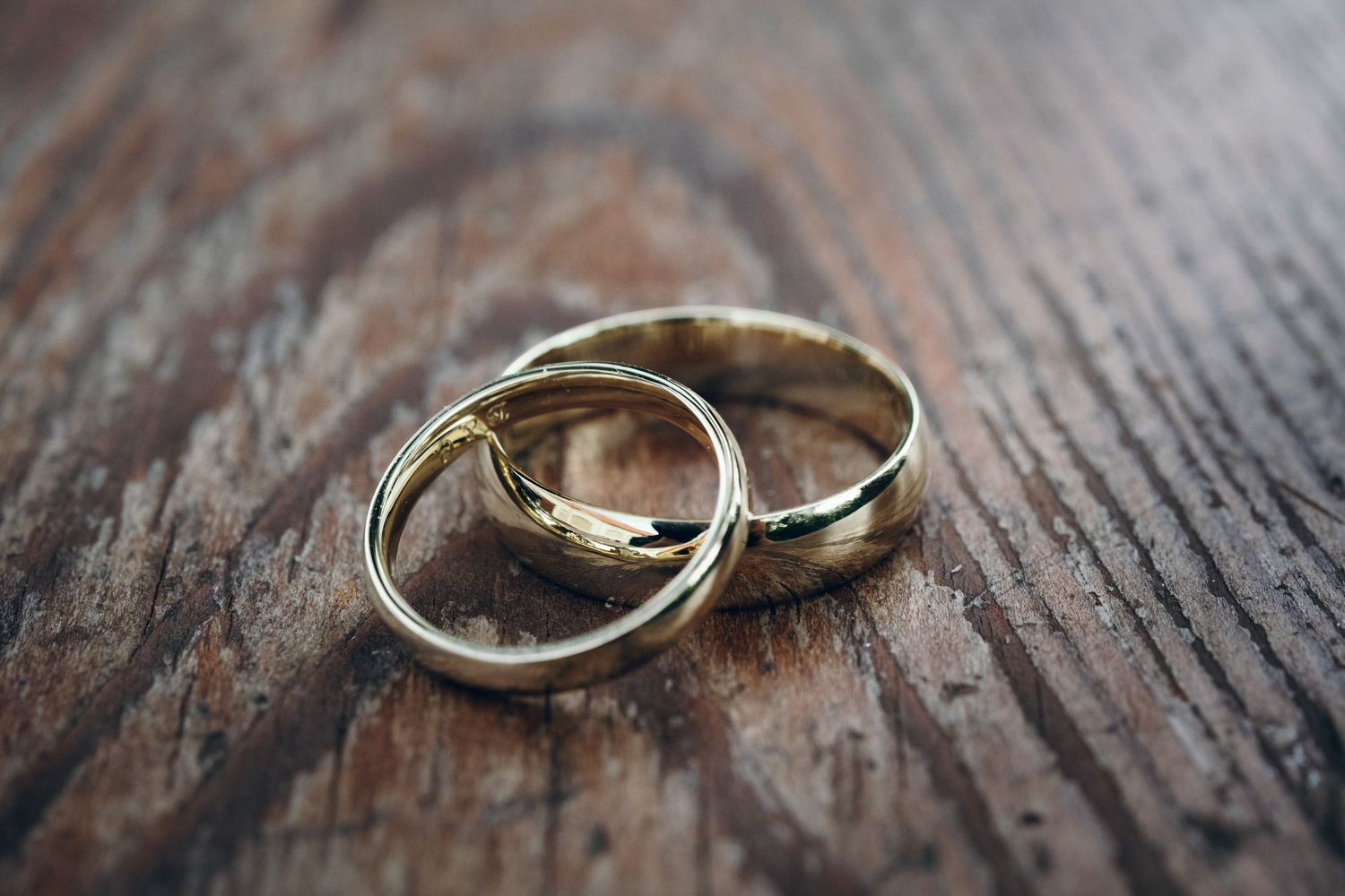 Wedding rings photographed in detail on rustic wooden surface.