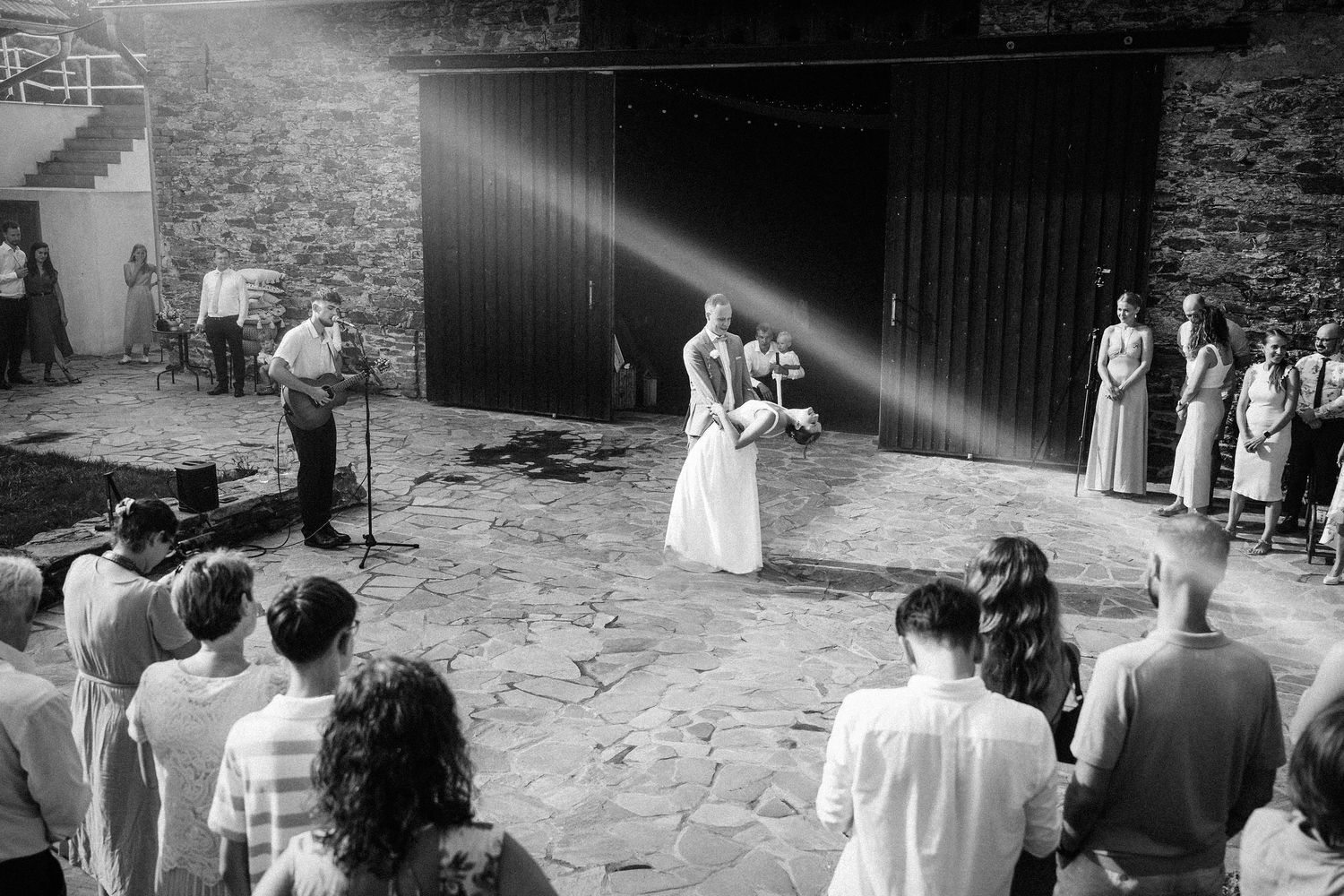 Black and white ceremony shot showing wedding guests gathered outdoors.