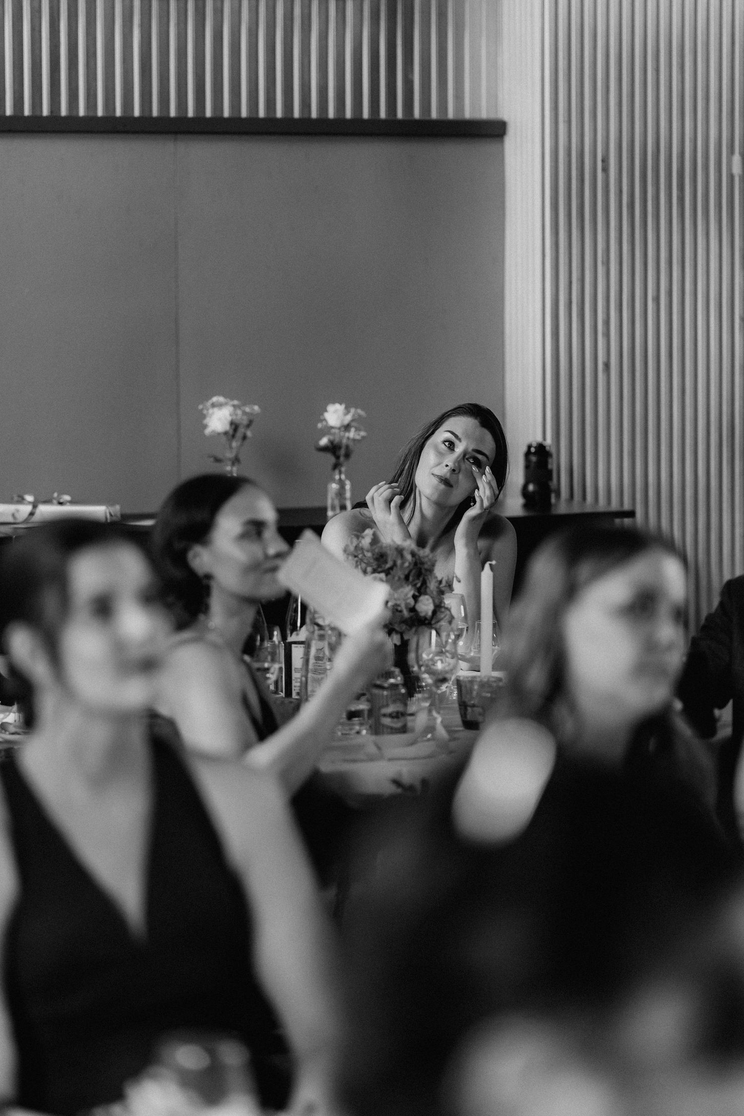 Black and white photo of wedding guests listening to speeches at reception dinner.