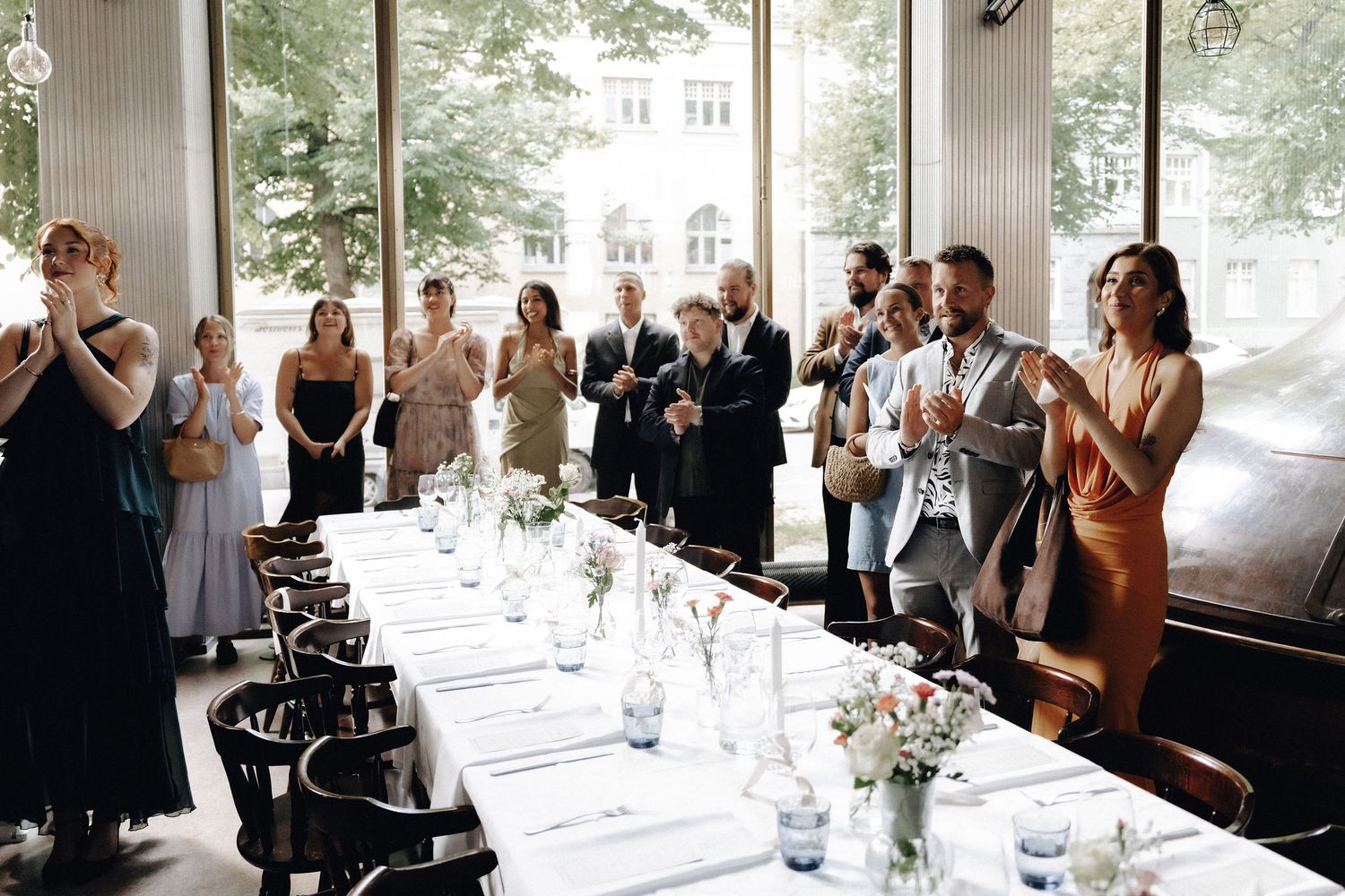 Wedding guests clapping and celebrating at a beautifully set long reception dinner table.