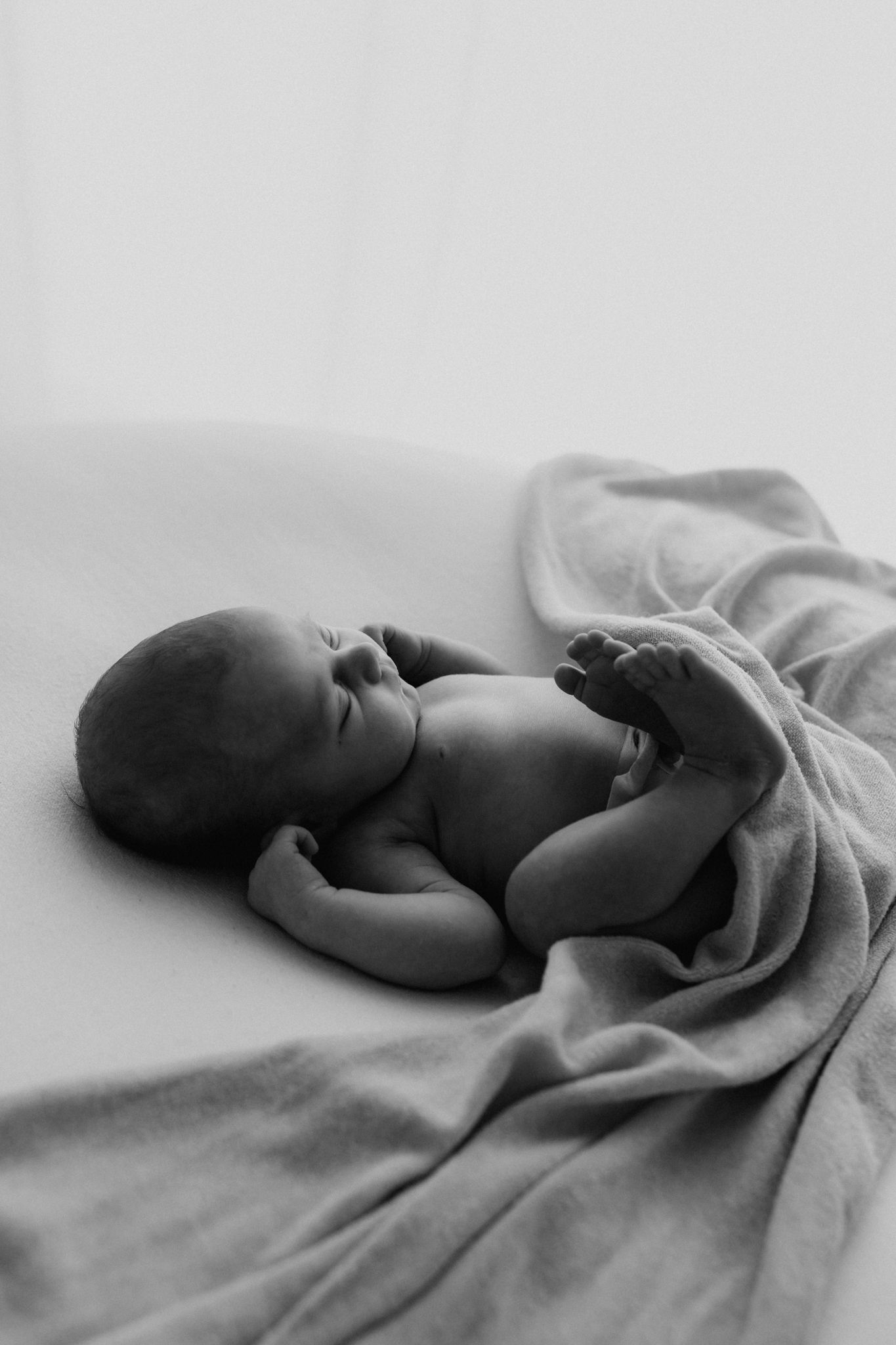 Peaceful newborn baby sleeping on a soft blanket in black and white photography.