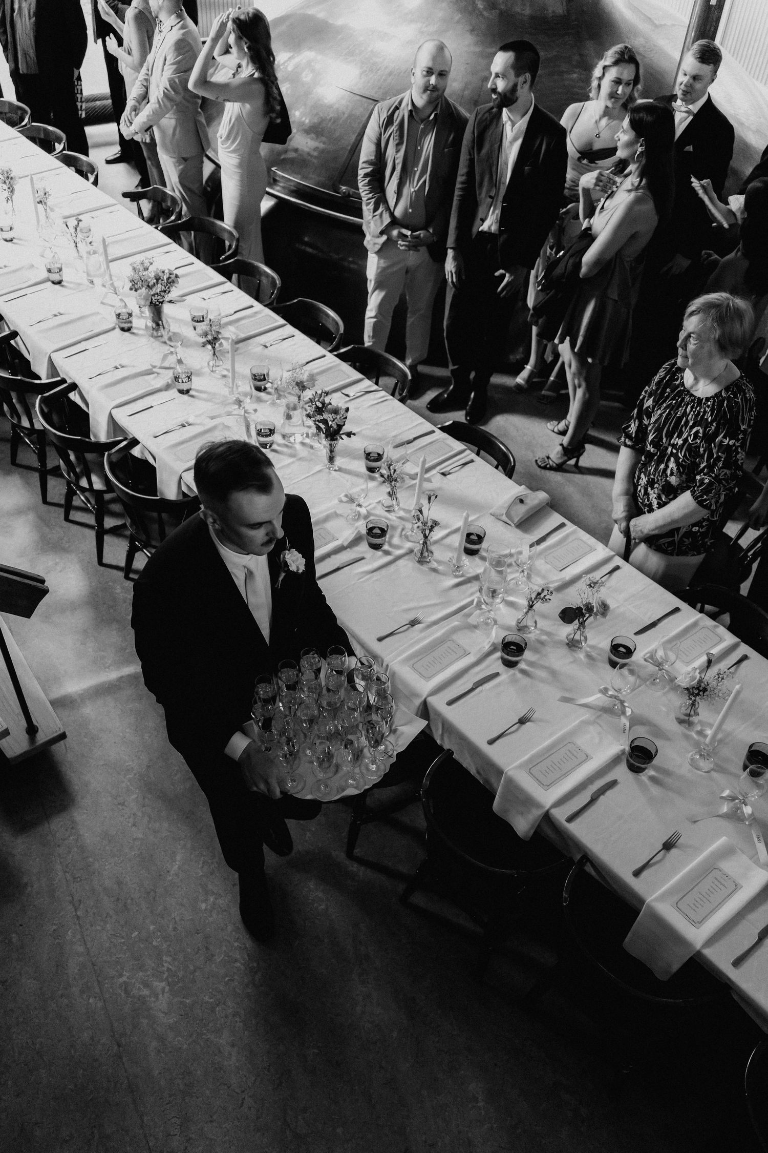 Black and white aerial view of waiter serving at elegant wedding reception dinner table.