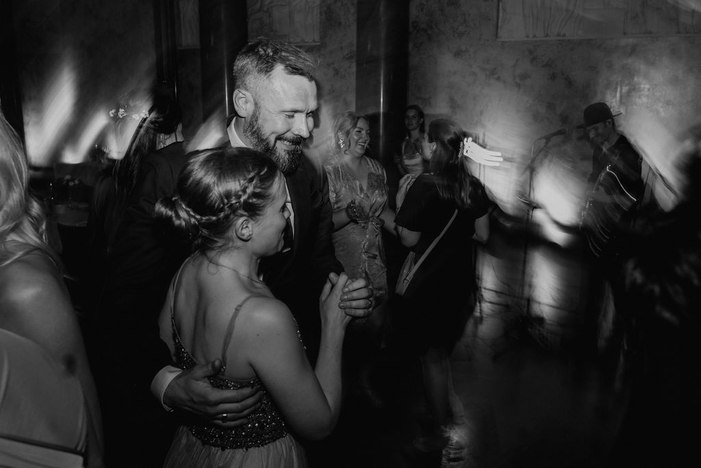 Couple shares intimate dance at wedding reception in black and white photo.