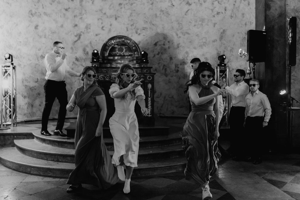 Bridesmaids and groomsmen perform a fun choreographed dance routine in black and white wedding photography.