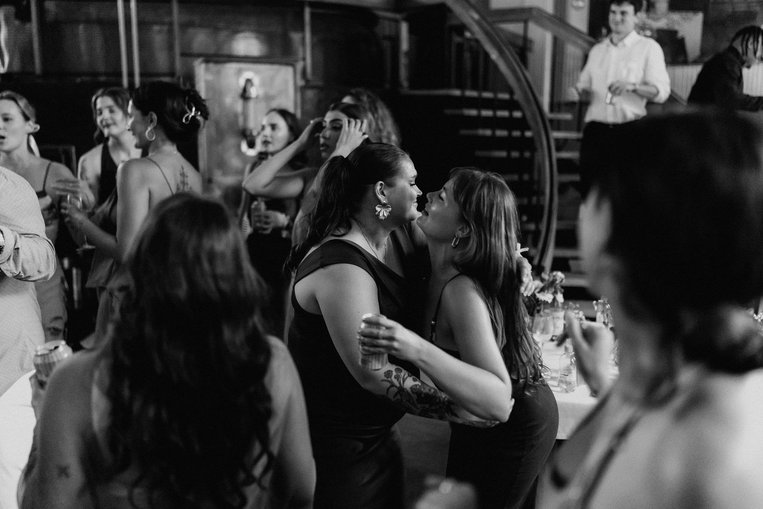 Guests share a kiss on the dance floor at a lively wedding reception.