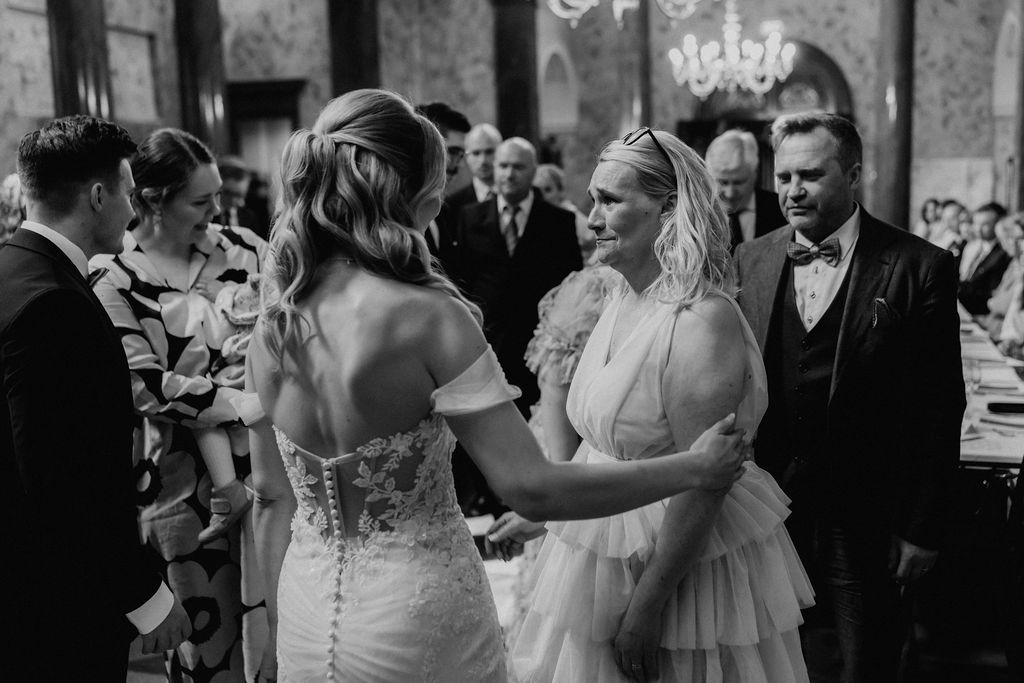 Black and white photo of bride sharing emotional moment with female guest at wedding.