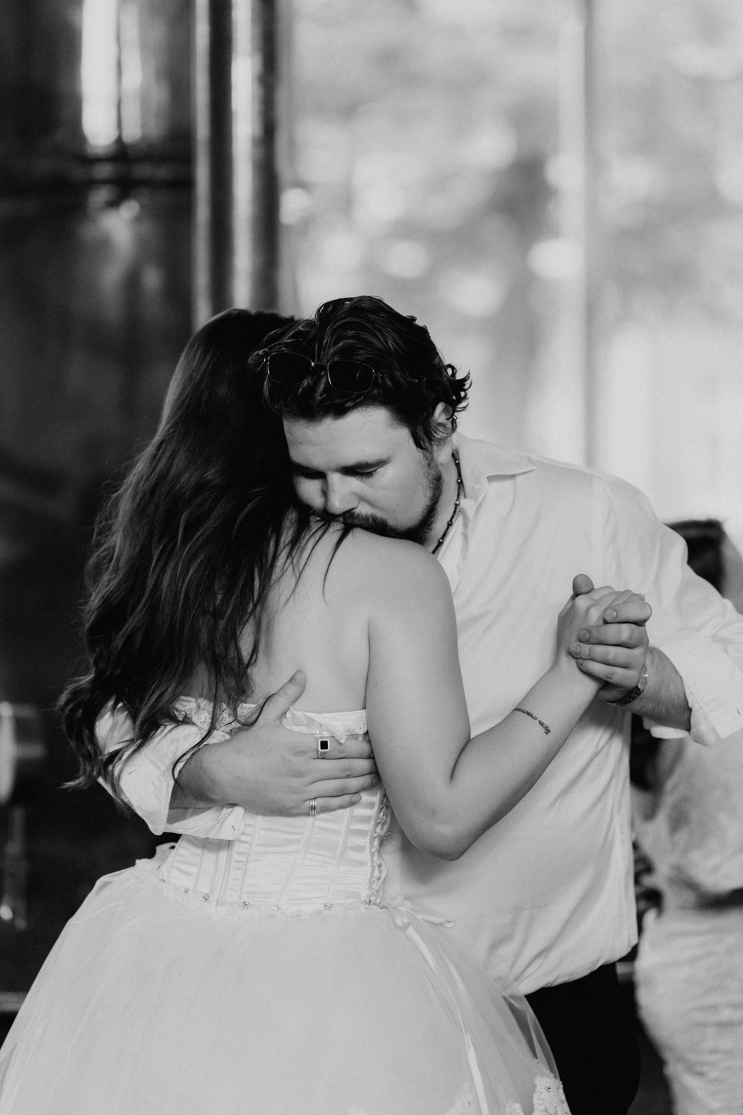 Couple shares romantic slow dance embrace at wedding reception in black and white.