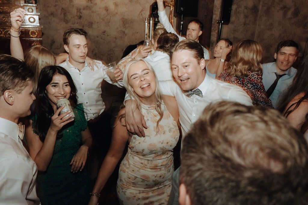 Wedding guests laughing and dancing together joyfully at a lively wedding reception party.