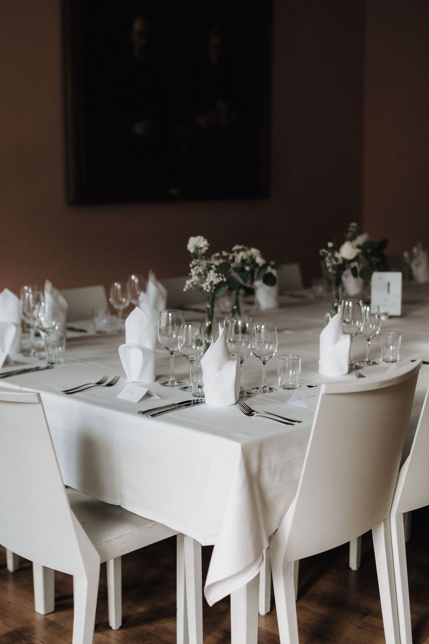 Elegant wedding reception table set with white linens, folded napkins, wine glasses, and floral centerpieces.