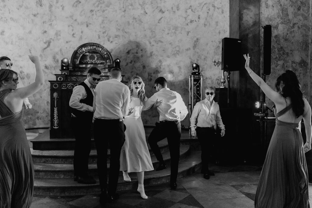 Wedding party performs lively choreographed dance routine captured in black and white photography.