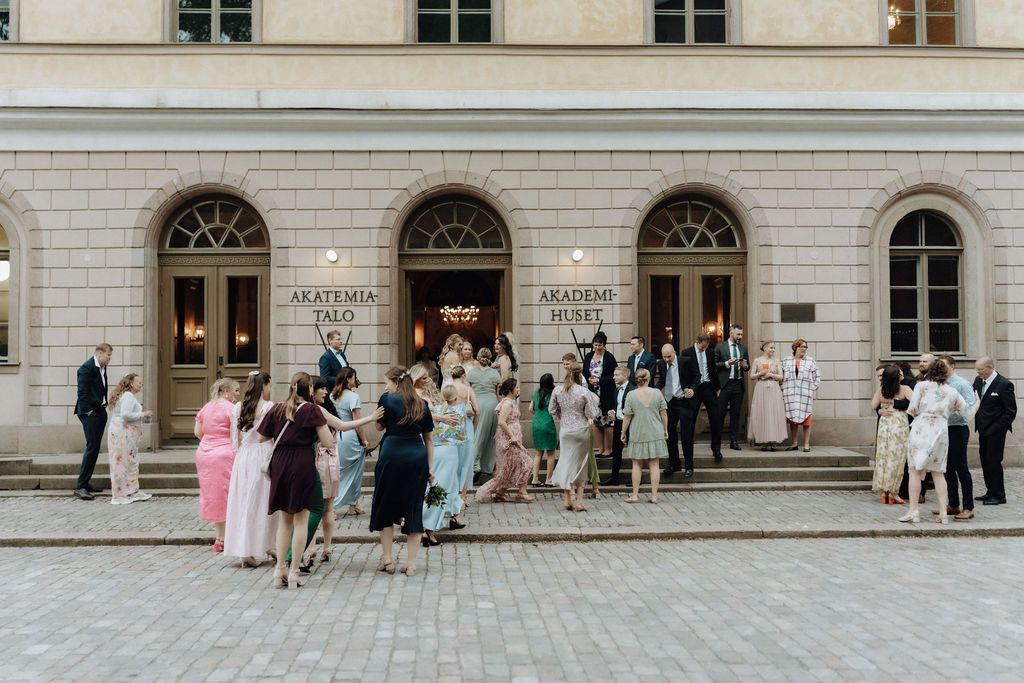 Wedding guests gathered outside the Akademia Muzyki building in elegant formal attire.