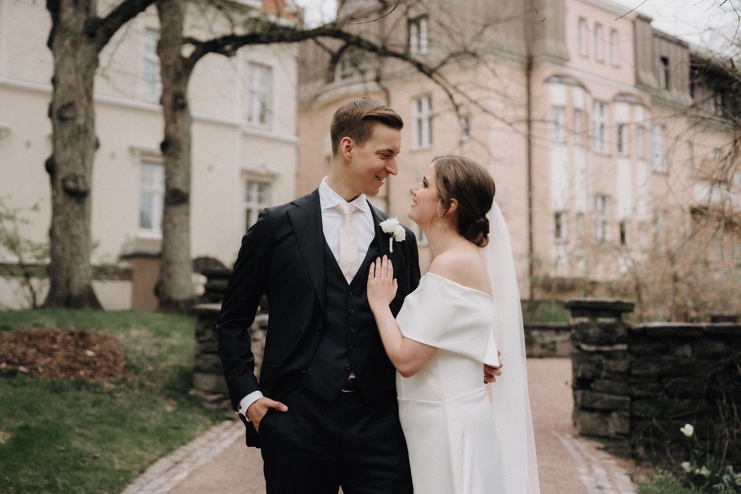 Elegant bride and groom share a romantic moment outdoors near a historic building on their wedding day.