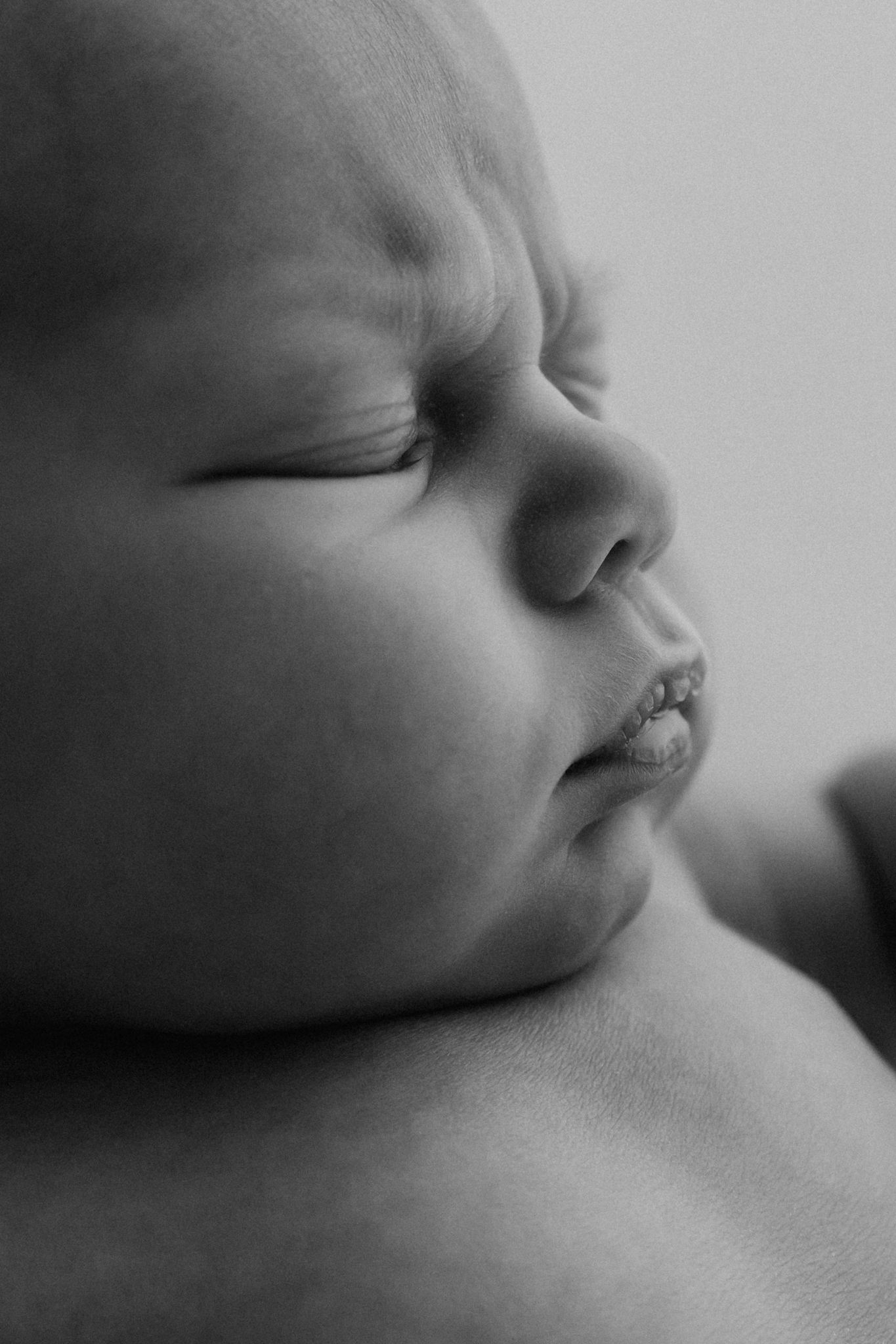 Close-up black and white portrait of peaceful sleeping newborn baby's face.