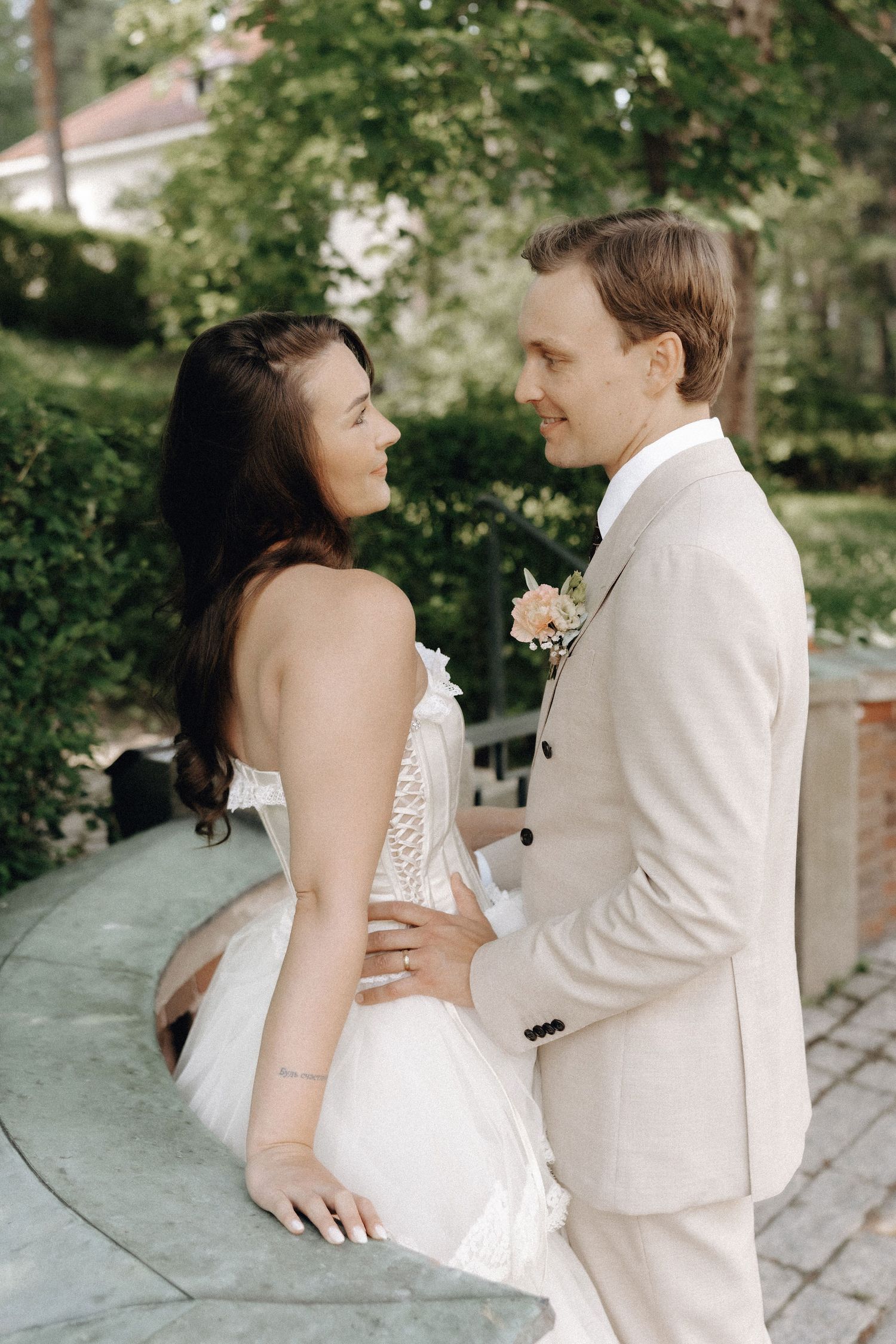 Bride and groom share an intimate moment, gazing into each other's eyes in a lush garden setting.
