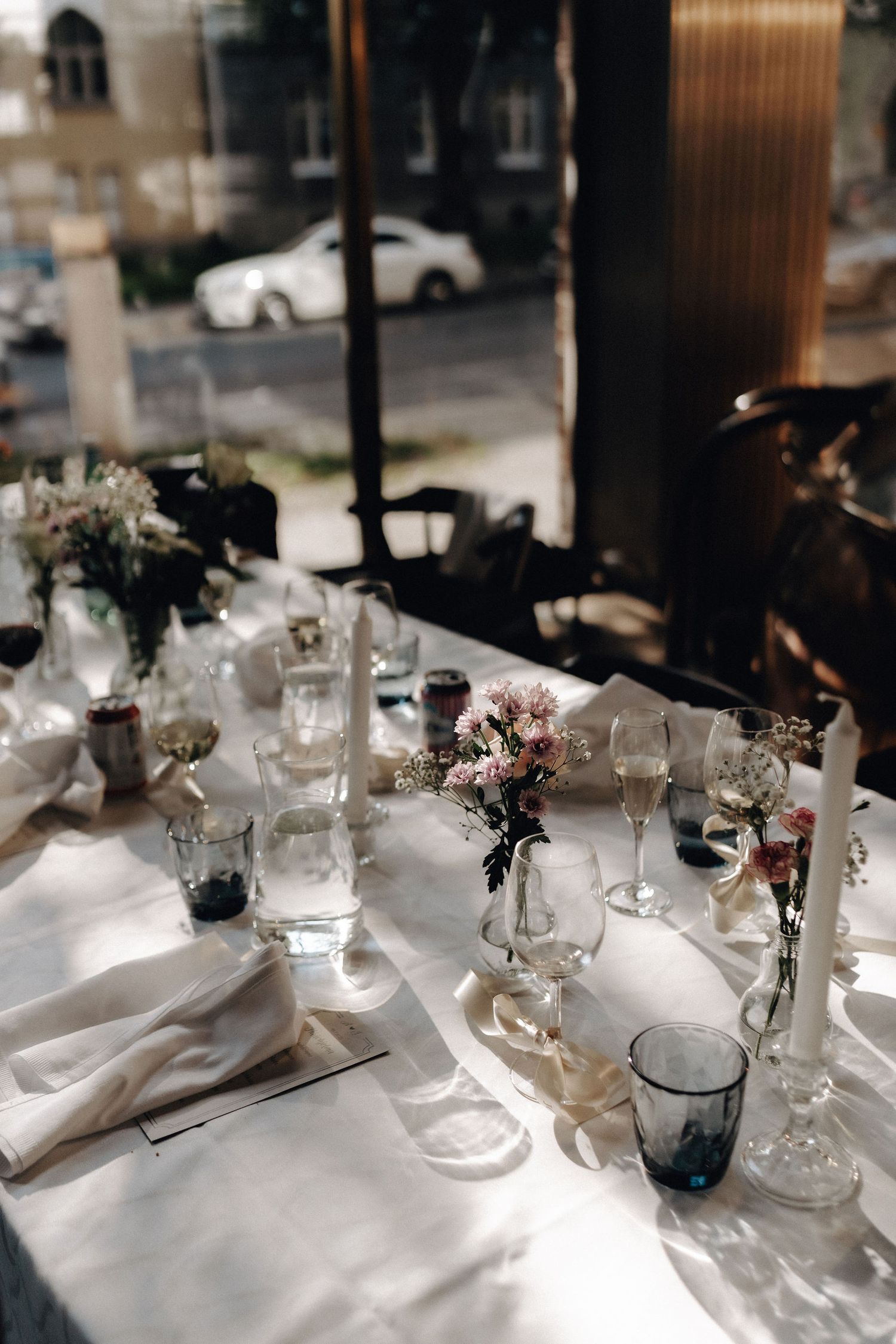 Elegantly set wedding reception table with white linens, glassware, and floral centerpieces.