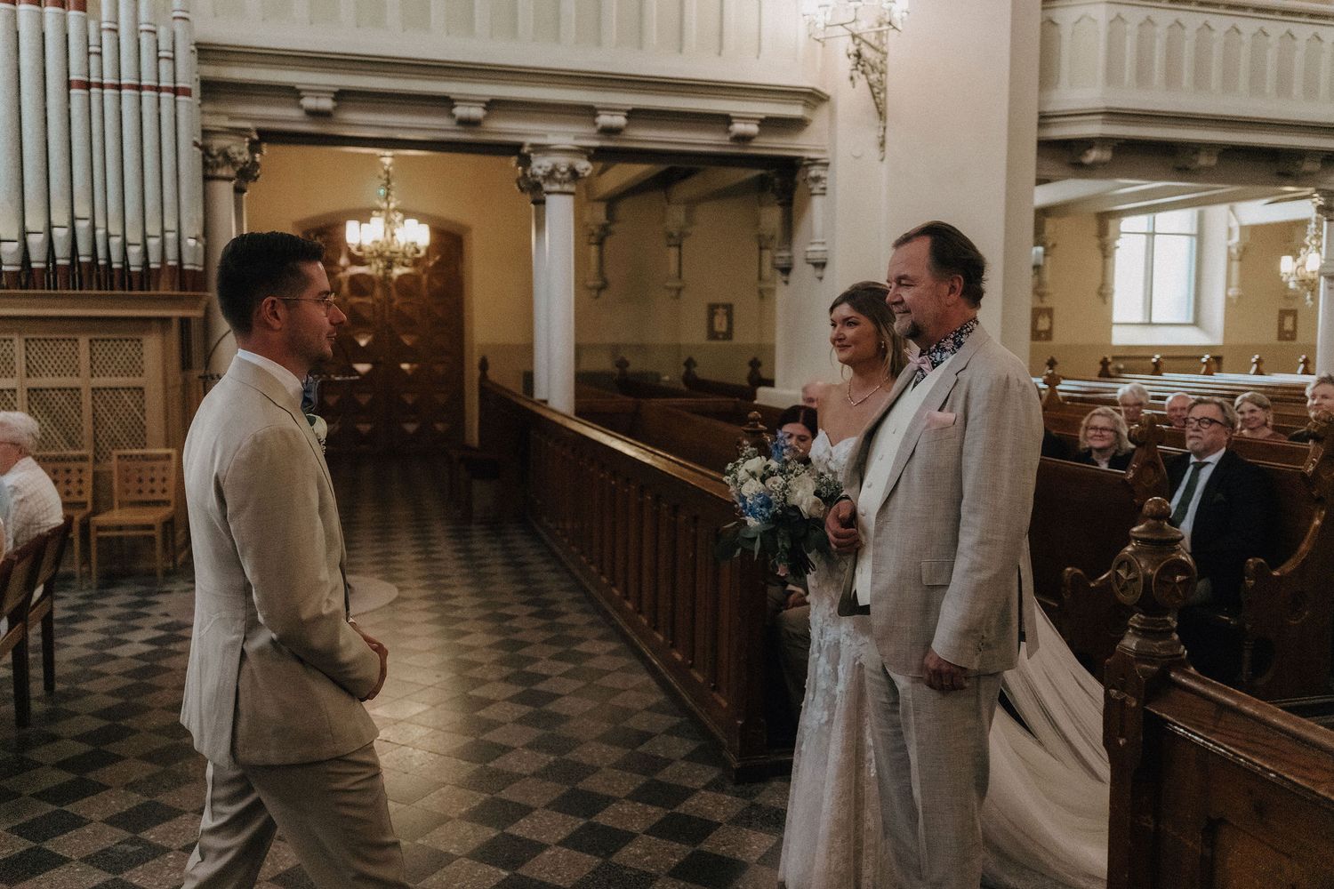 Groom meets bride and her father at the altar during an elegant church wedding ceremony.