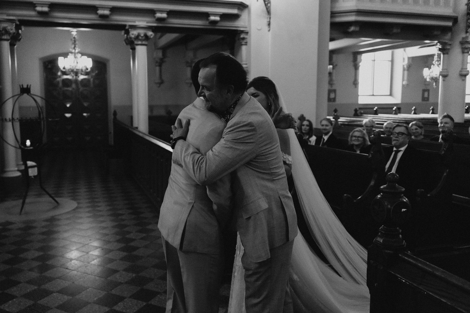 Emotional black and white photo of bride and groom embracing at the church altar.