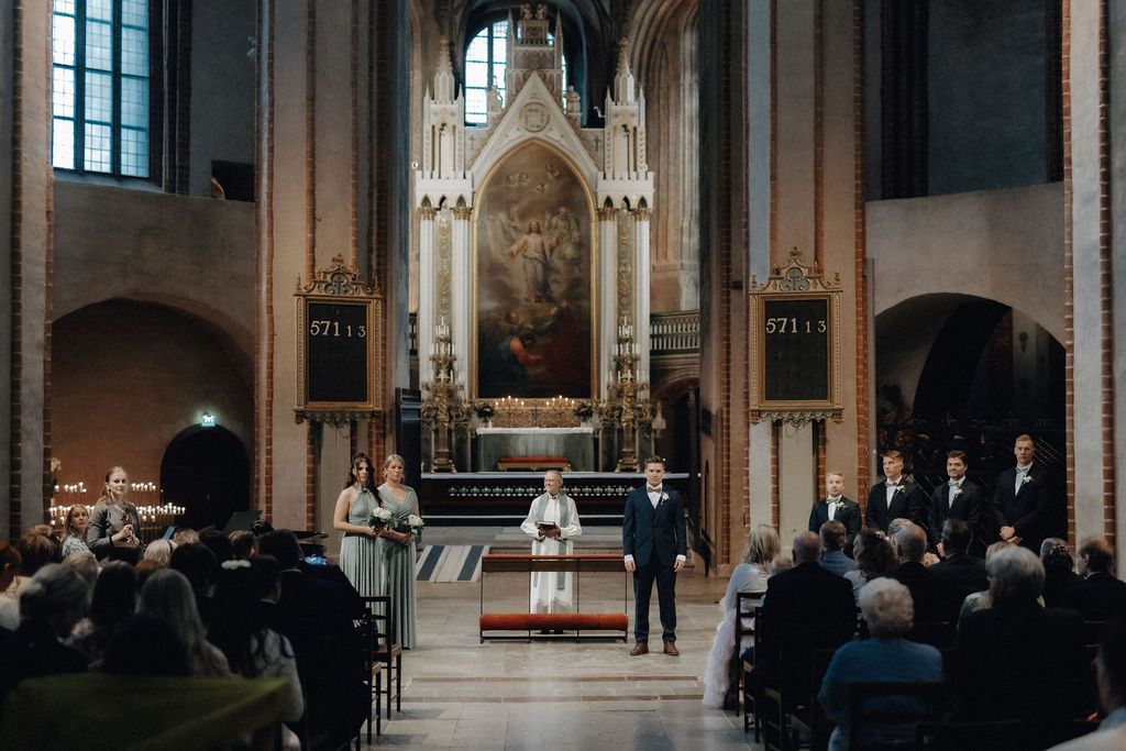 Bride and groom stand at the altar of an ornate Gothic church during wedding ceremony.