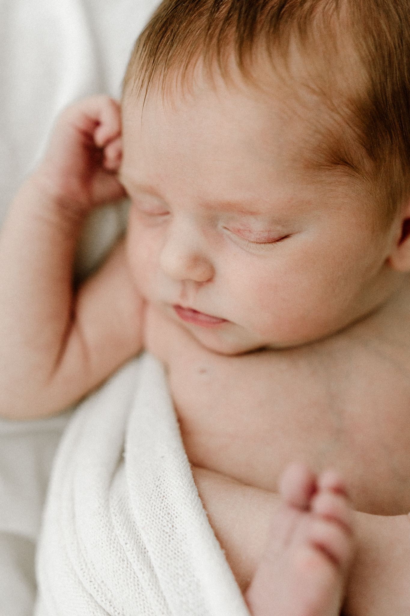 Close-up of serene sleeping newborn baby with delicate features and tiny hands.