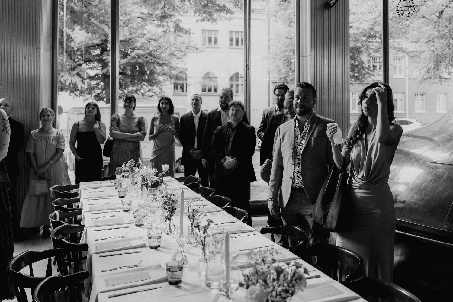 Wedding guests applauding at elegant reception dinner table in black and white photography.