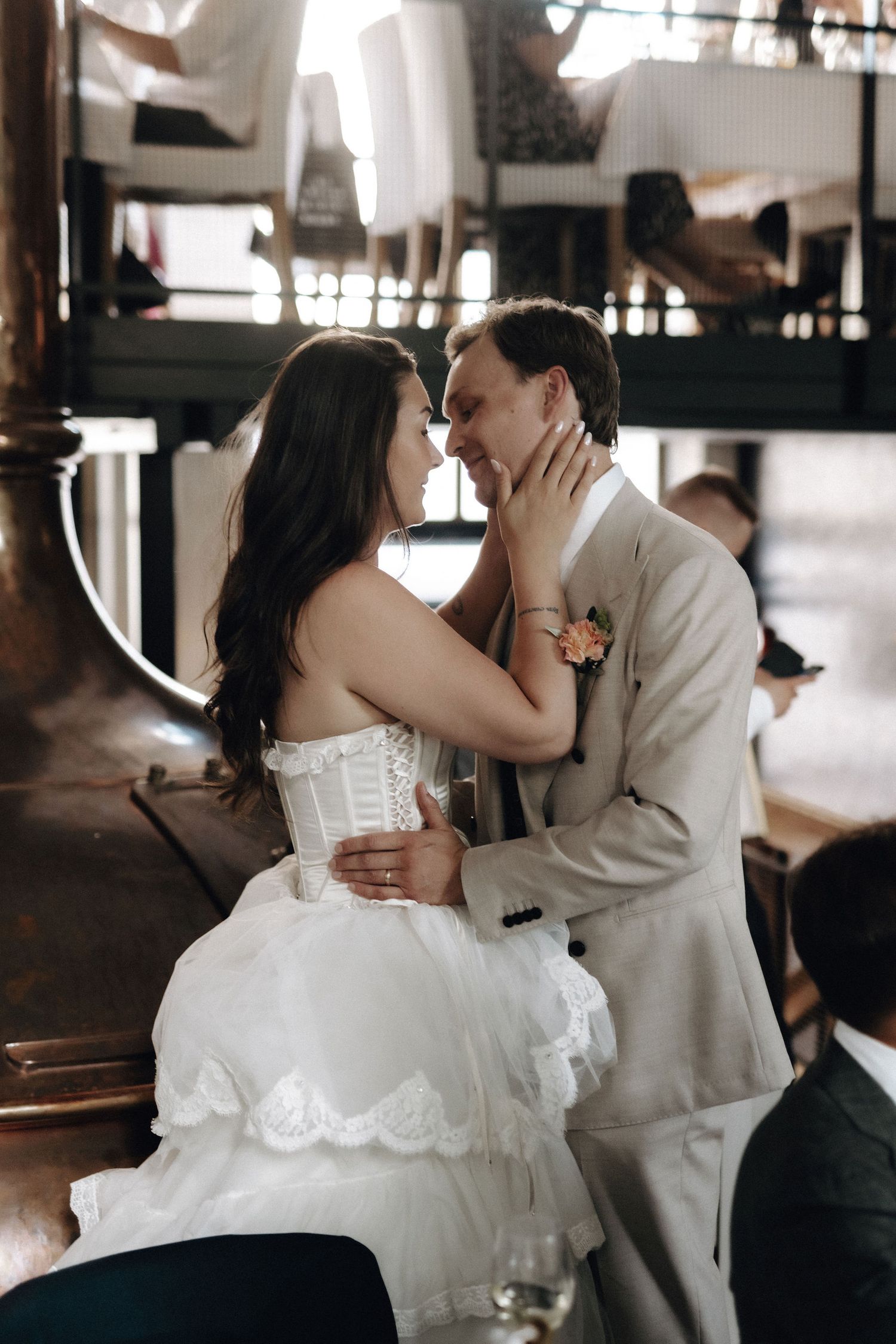 Bride and groom sharing intimate moment, touching foreheads at wedding reception table.