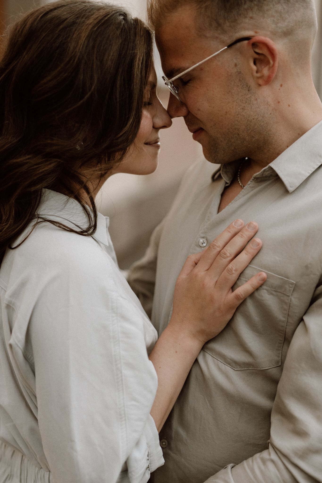 Romantic couple in an intimate moment, woman placing hand on mans chest, foreheads touching.