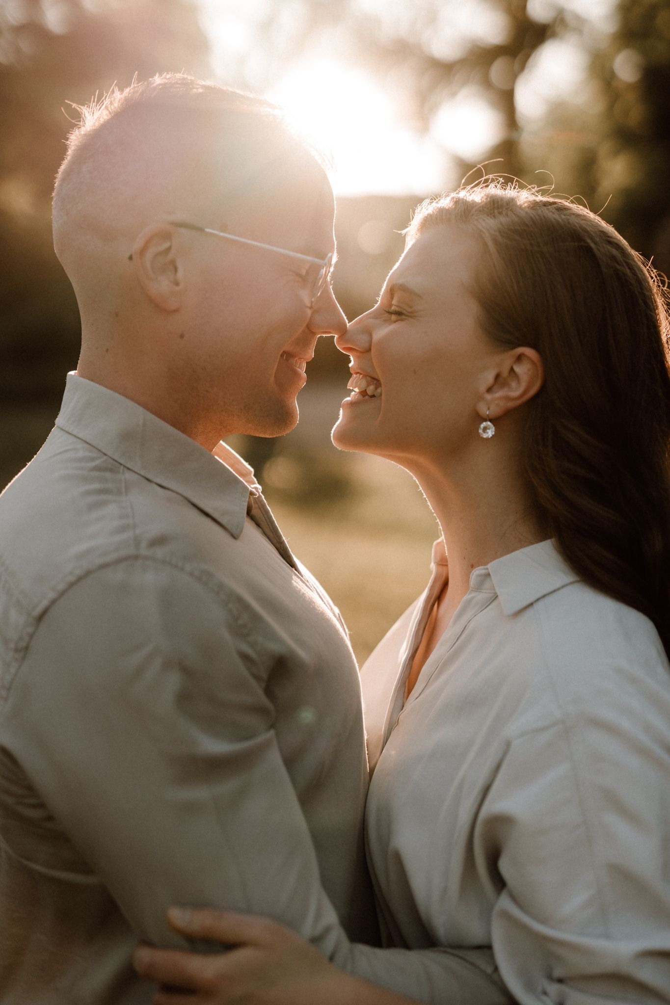 Romantic couple smiling nose-to-nose in warm golden sunset backlight outdoors.