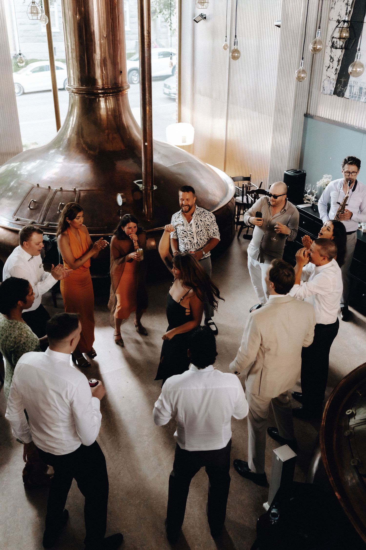 Wedding guests dancing in a circle at a brewery reception venue.