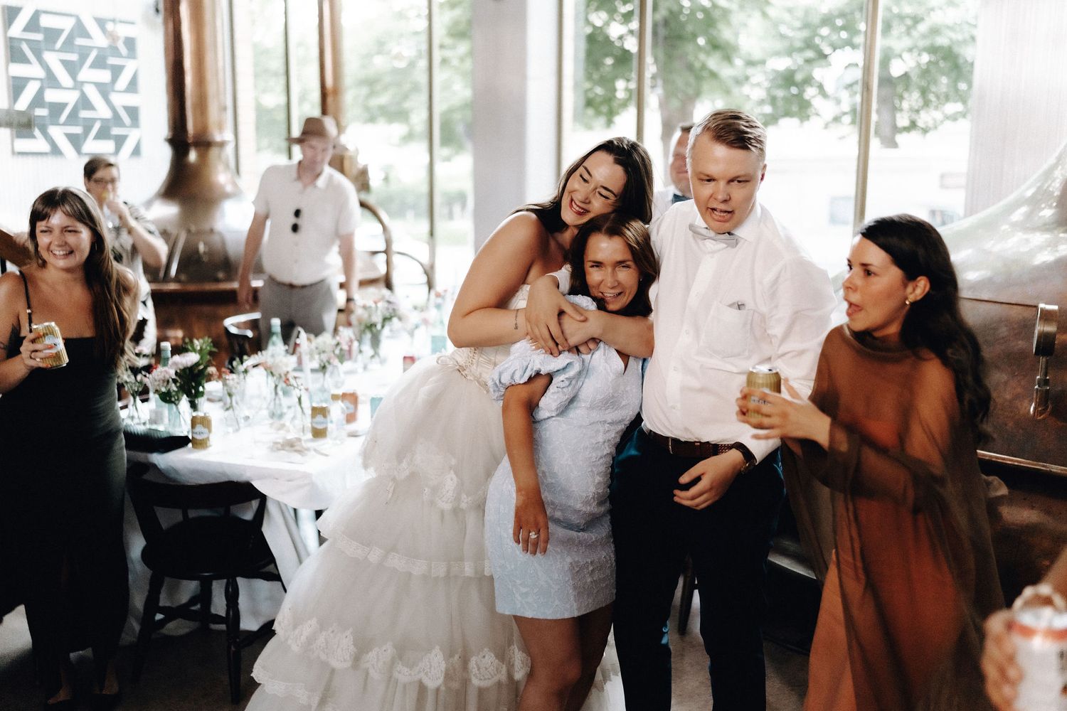 Bride in ruffled white gown hugs guests at elegant wedding reception venue.