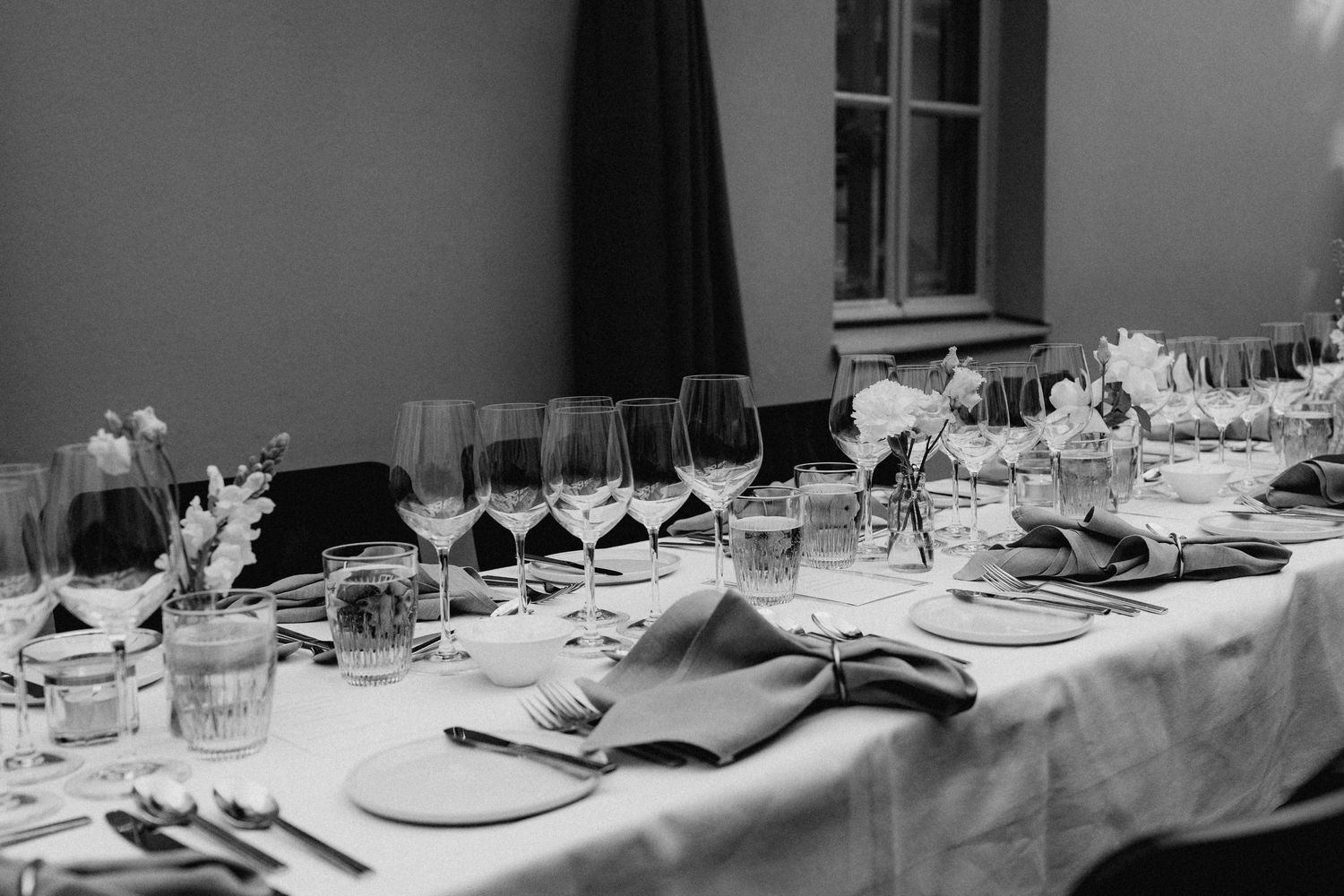 Elegant wedding reception table set with crystal wine glasses, folded napkins, and floral centerpieces in black and white.