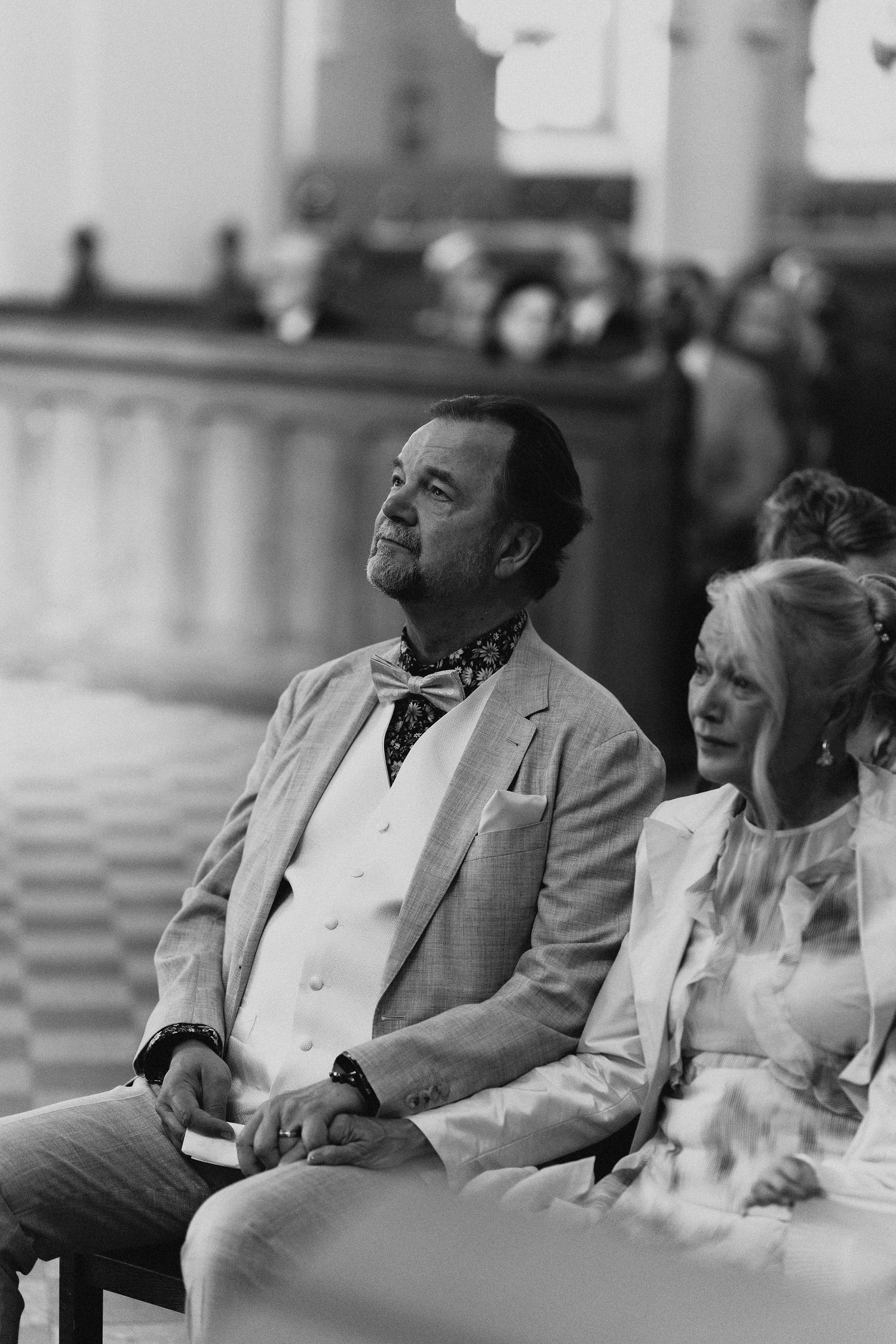 Black and white photo of wedding guests seated in church pews during ceremony.