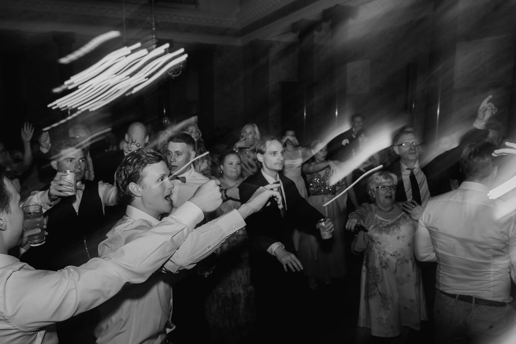 Black and white wedding reception dance floor with guests dancing and sparklers creating light streaks.