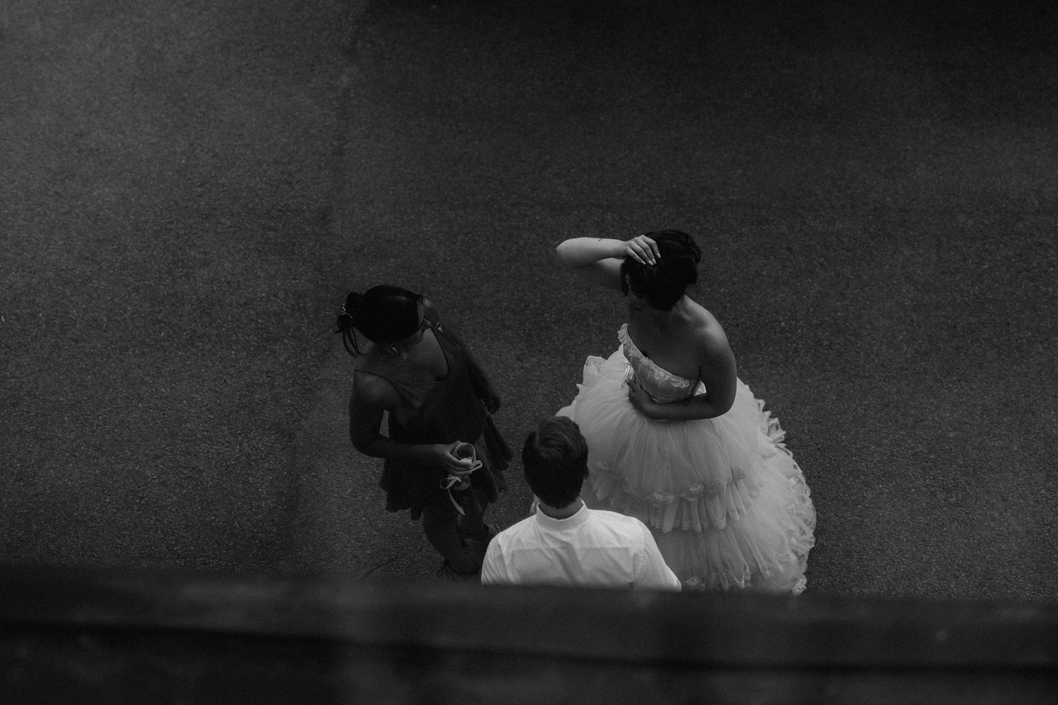 Black and white aerial view of bride in tulle gown with guests at wedding reception.