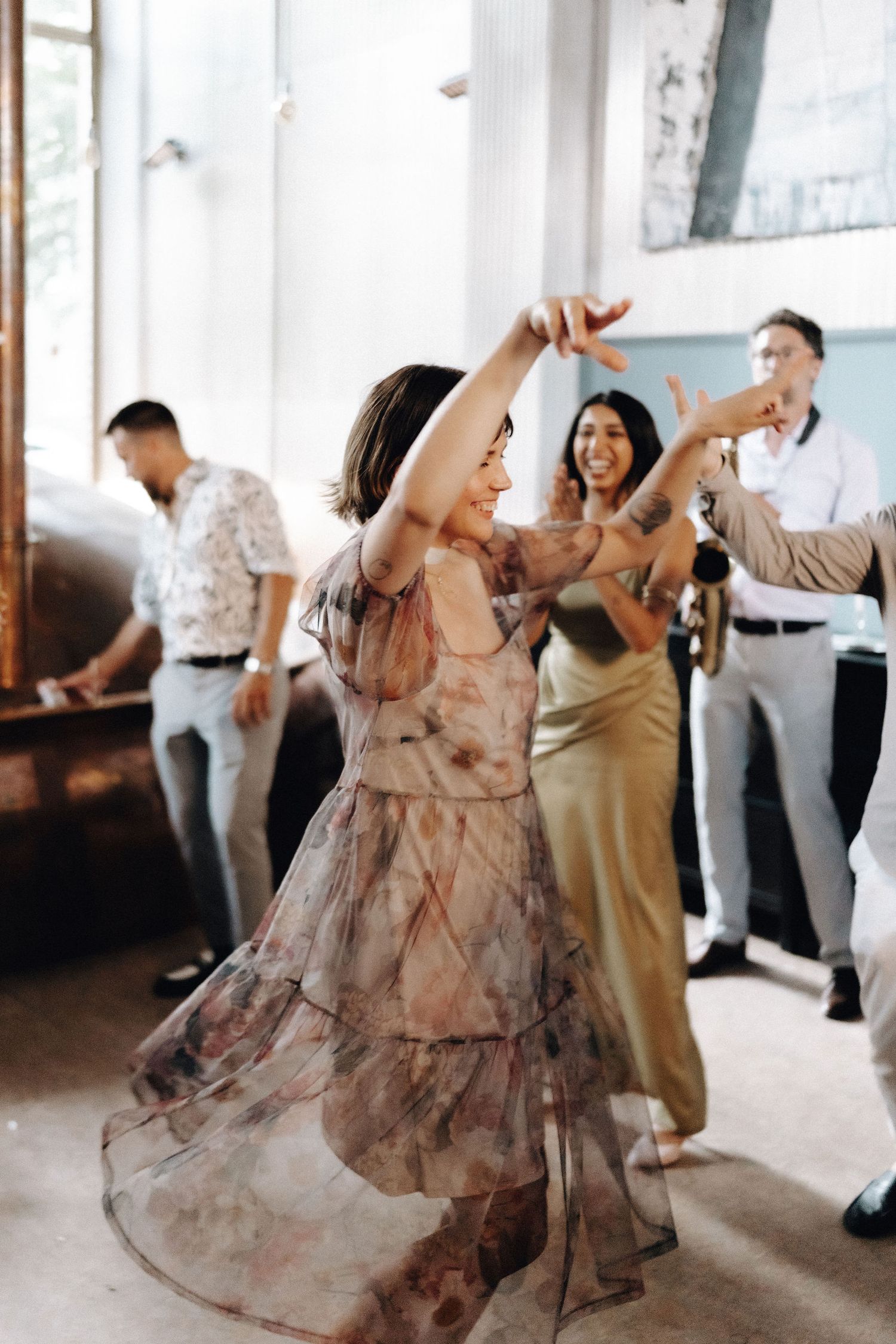 Woman in floral dress twirling joyfully on the dance floor at a wedding reception.