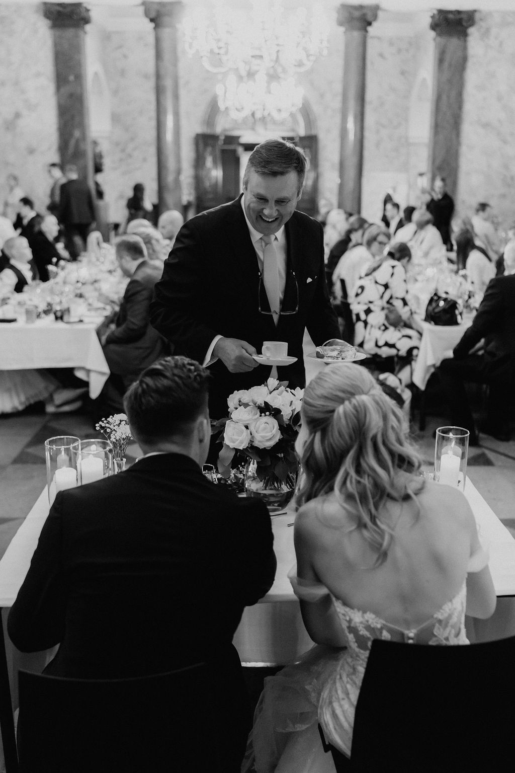 Black and white overhead view of groom presenting something to the bride at the wedding table.
