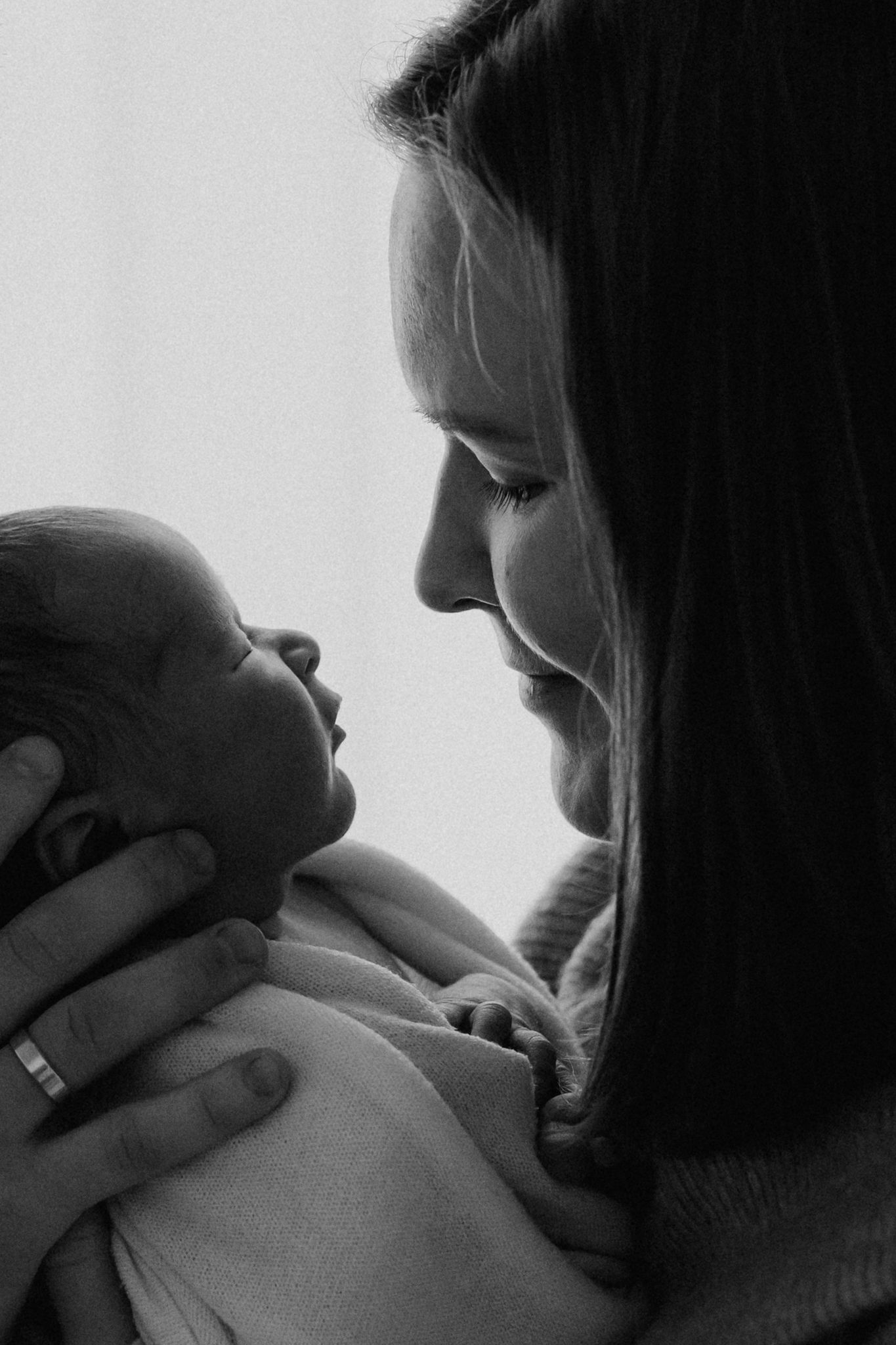 Black and white portrait of a smiling mother gazing lovingly at her newborn baby.