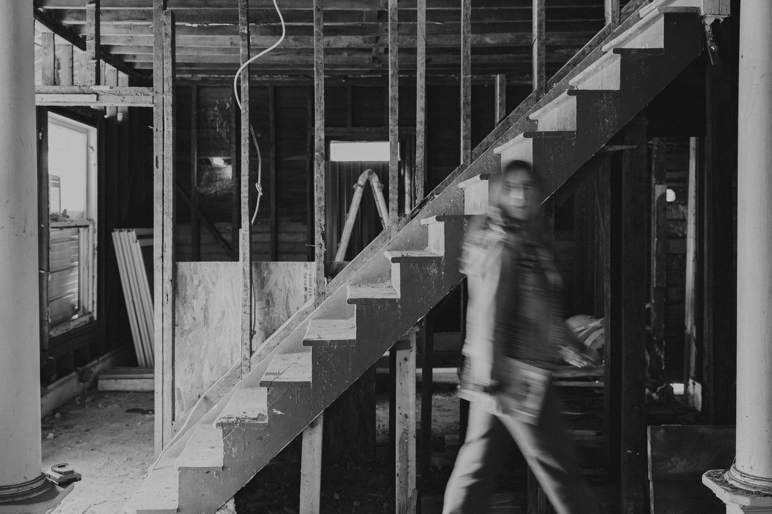 motion blur photo of woman walking in front of stairs in an unfinished home