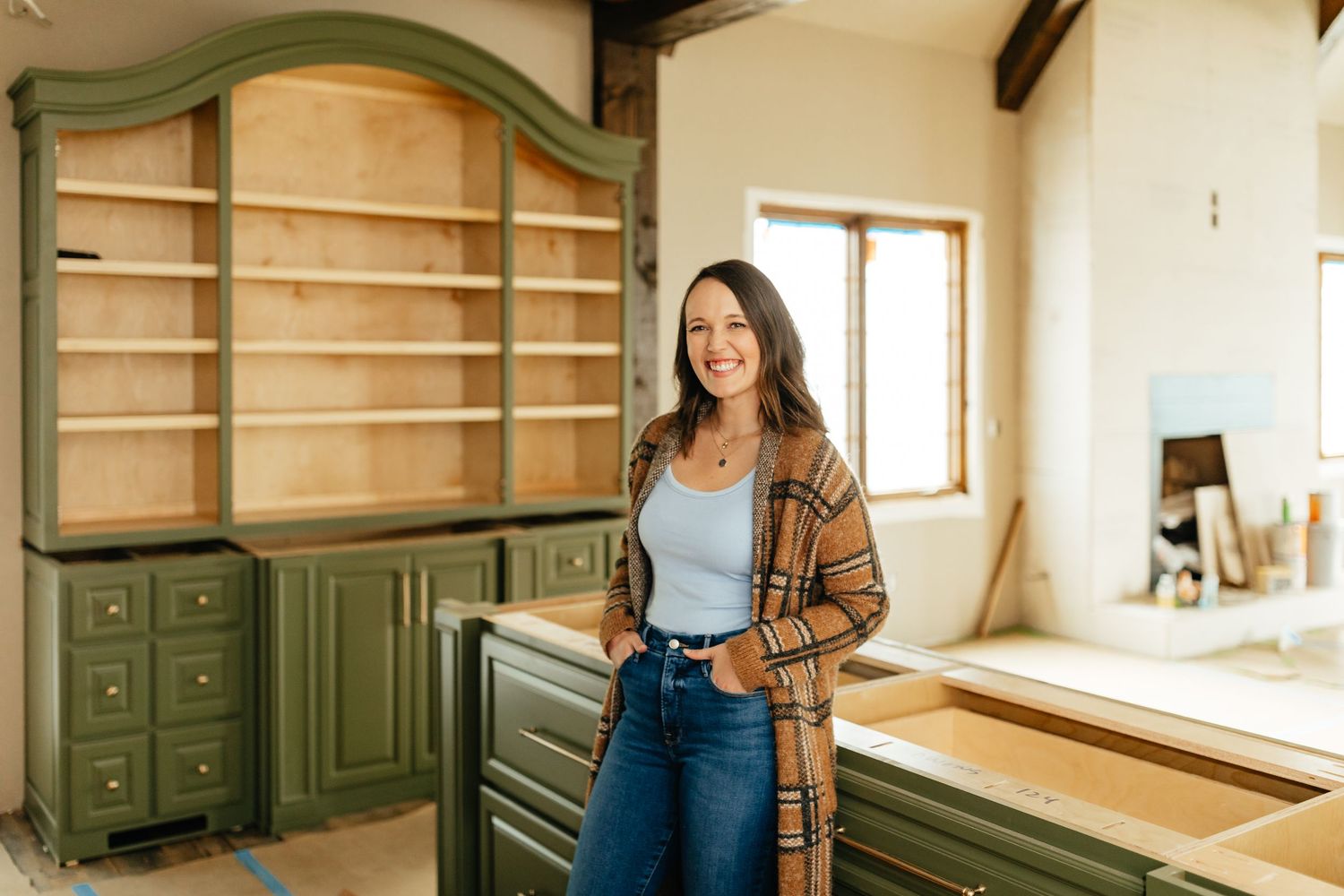 Lindsay Lattner Interiors headshot inside unfinished kitchen with green cabinets