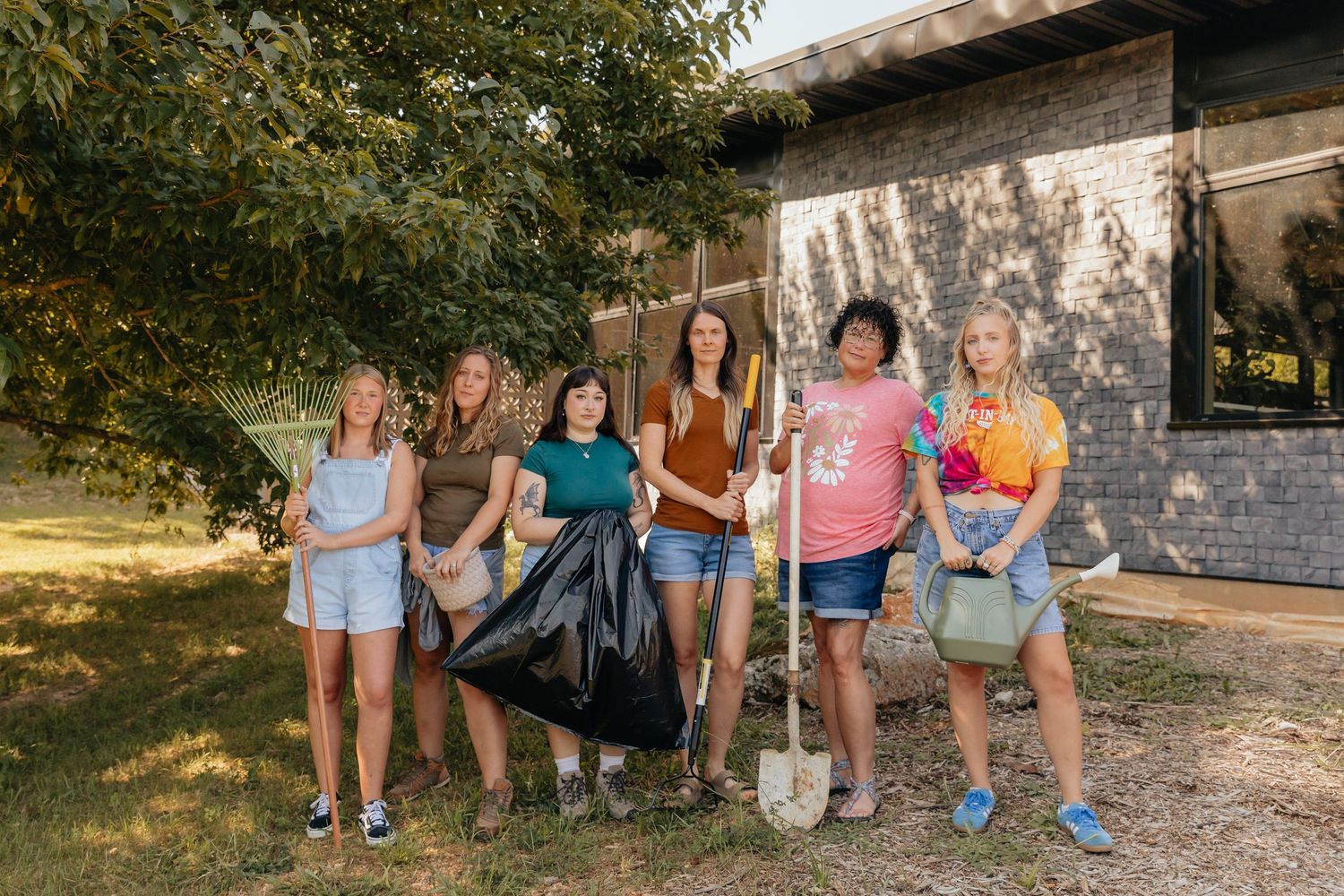 Juniper Gardens team outside holding various gardening tools