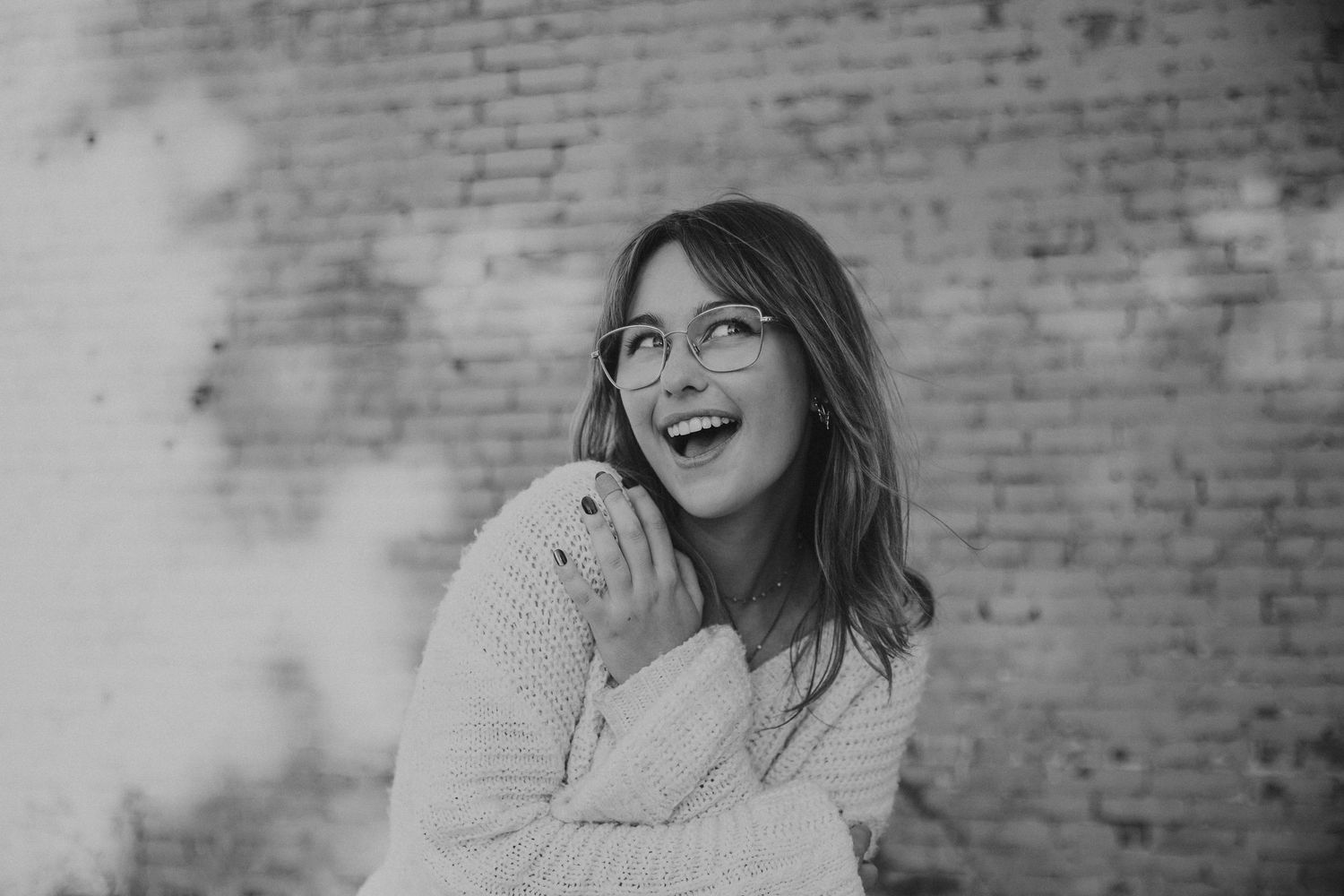 senior photos on commercial street in front of brick wall