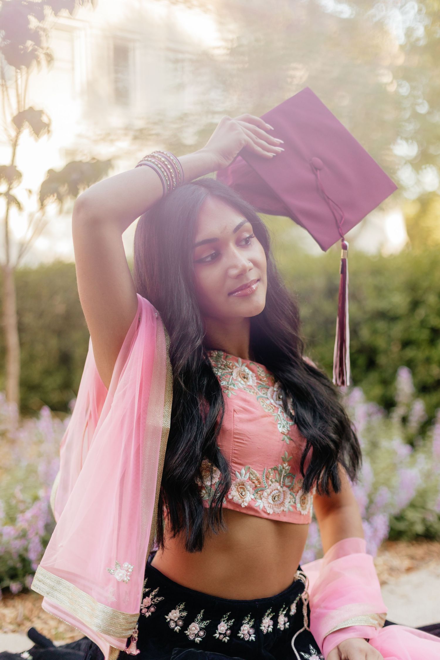 grad in lehenga holding grad cap over her head
