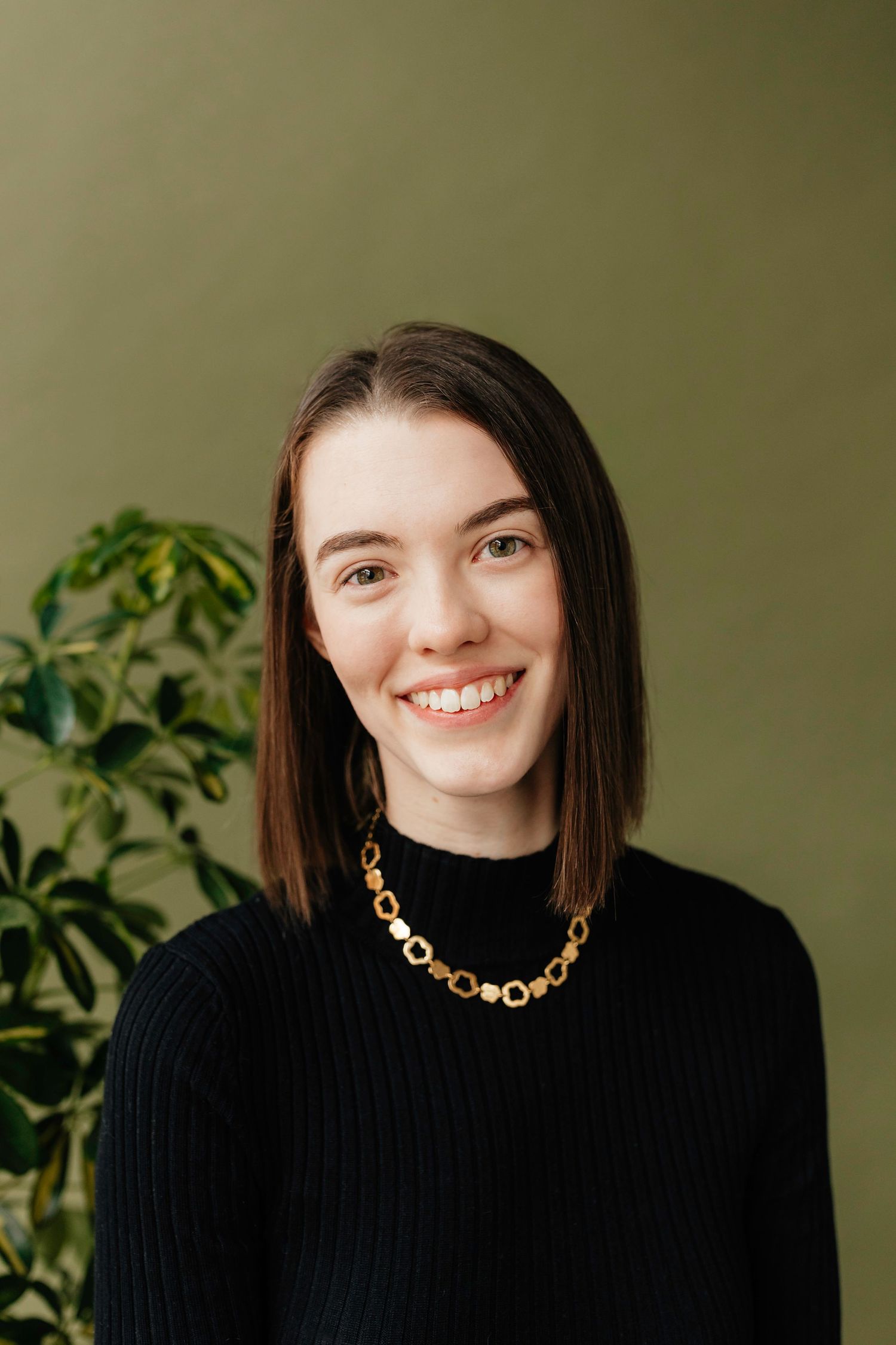 headshot of girl with gold necklace against a green backdrop